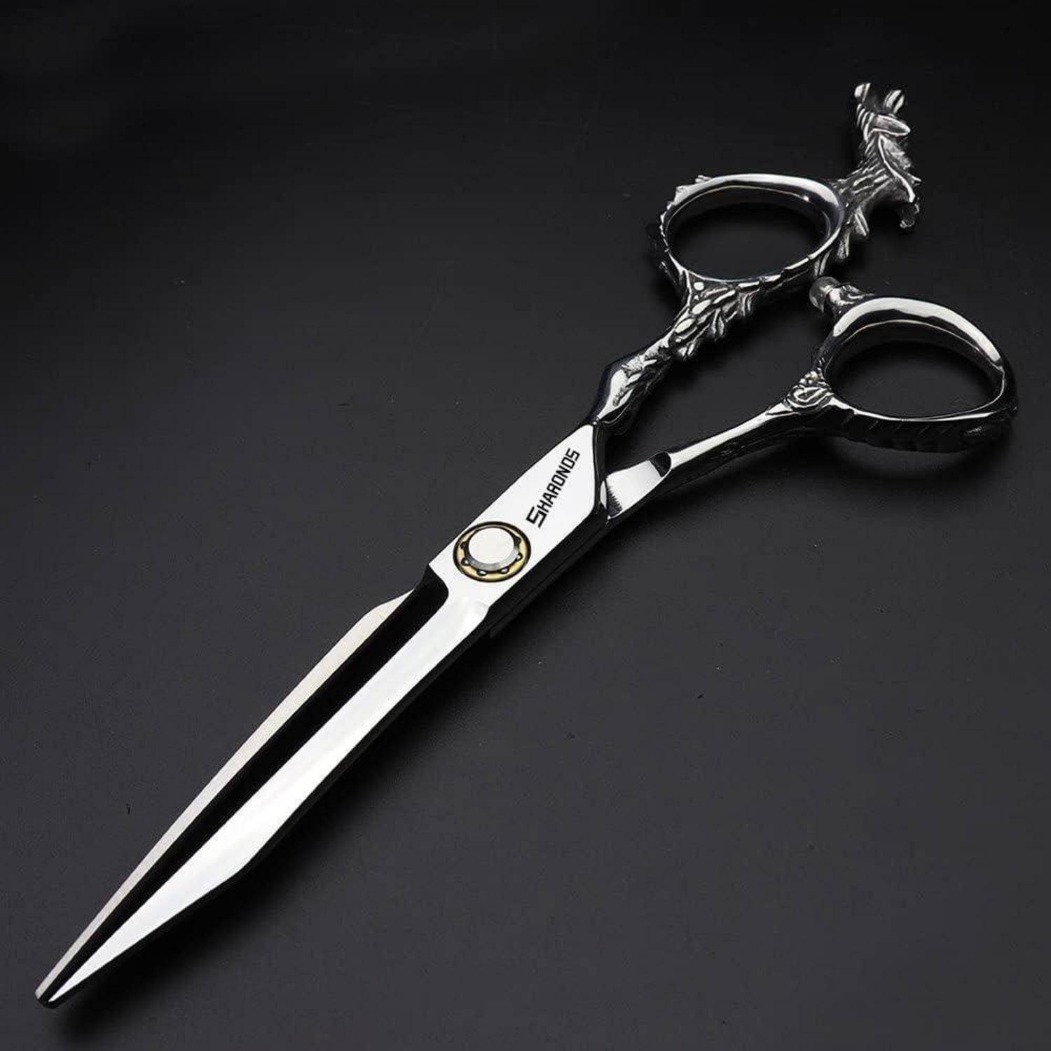 Dekorative Silber-Haarschneideschere mit ornamentalem schwarzem Griff, auf dunklem Hintergrund gezeigt.