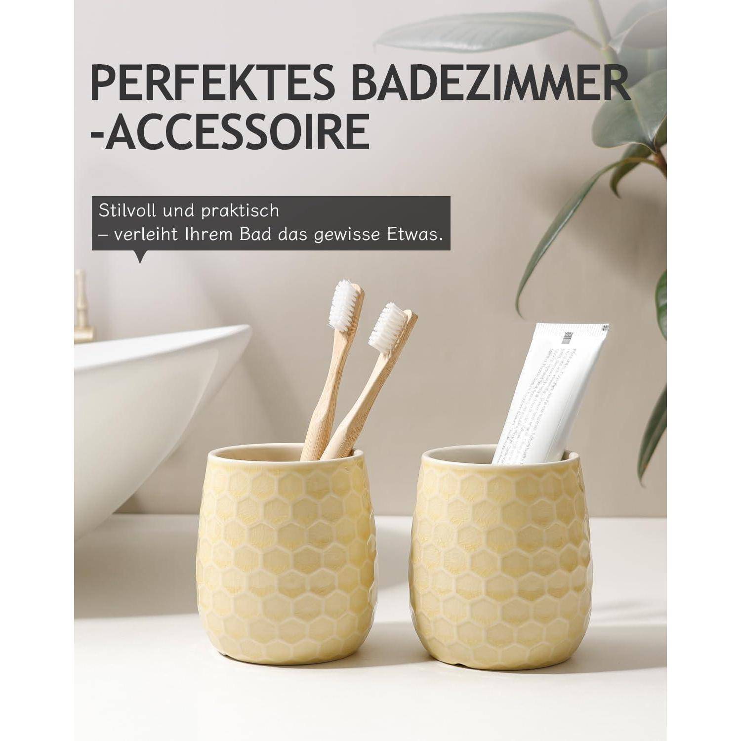 Badezimmeraccessoires-Set mit zwei gelben, sechseckig gemusterten Bechern, die Zahnbürsten und eine Zahnpastatube halten, beschriftet mit „PERFEKTES BADEZIMMER-ACCESSOIRE