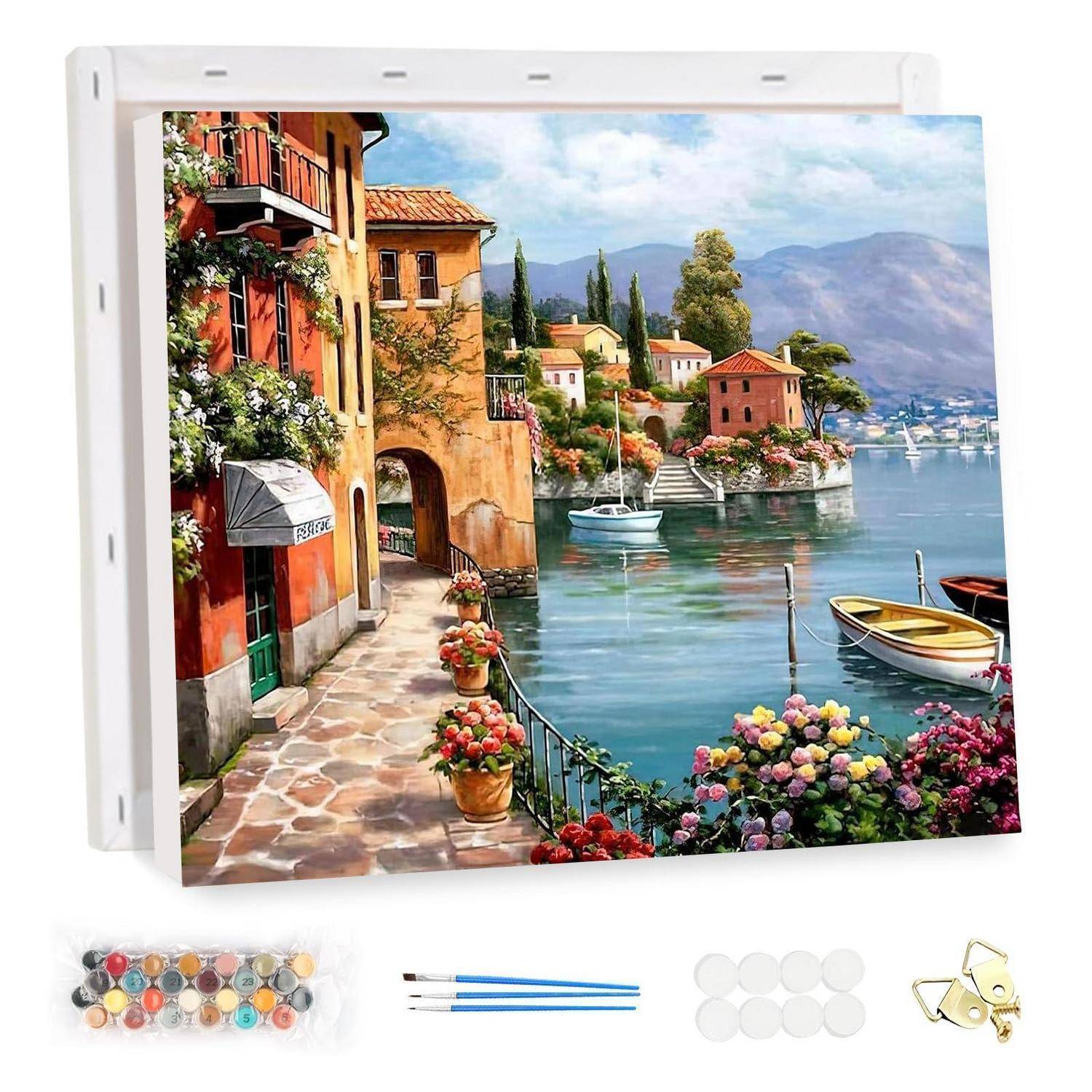 Leinwanddruck eines Dorfes am See mit Booten, bunten Blumen und Bergen, dargestellt mit Aufhänghardware und Malzubehör darunter.