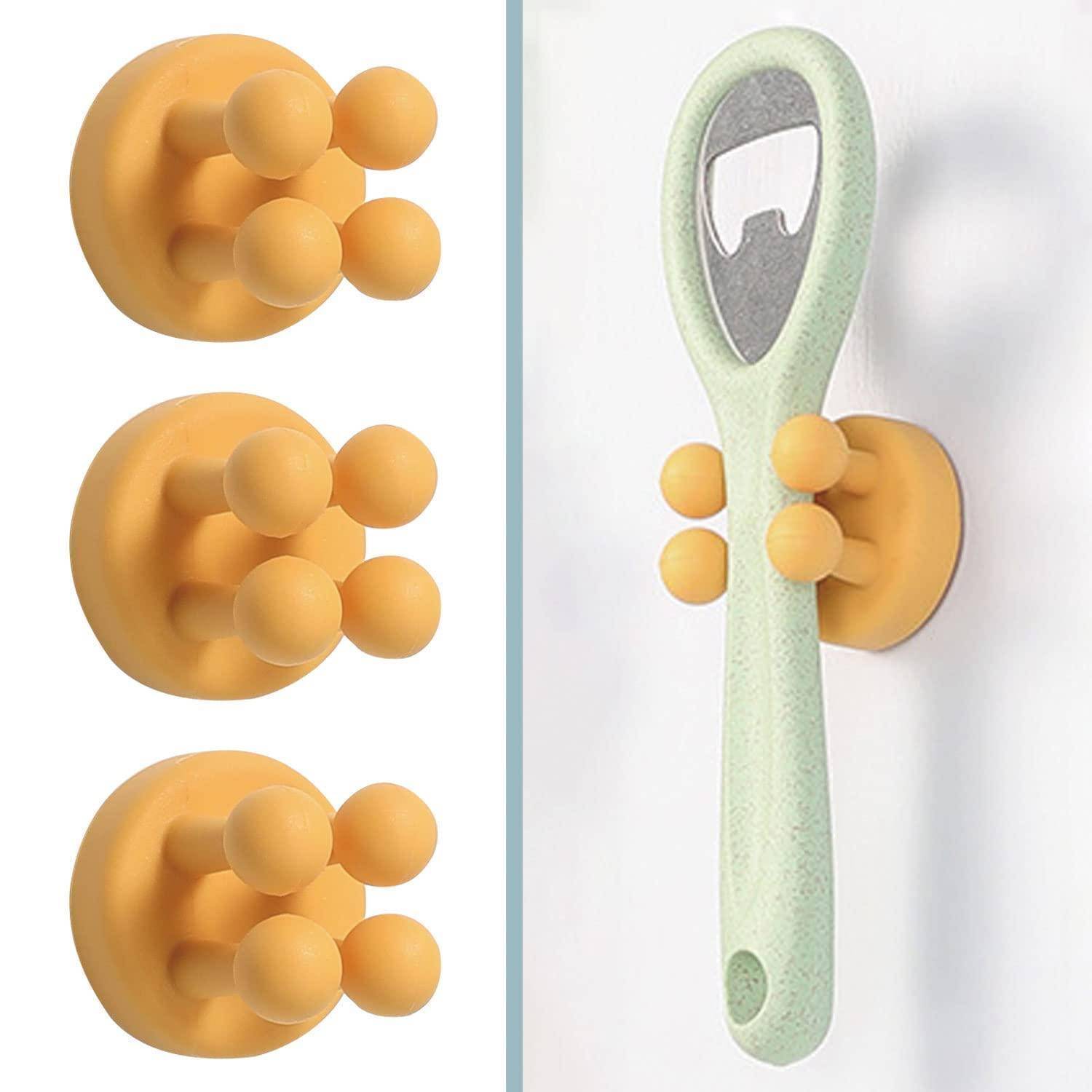 Orange Saugnapf-Wandhaken und ein an der Wand angebrachter Zahnbürstenhalter, die zeigen, wie die Halter Gegenstände mit runden Stiften greifen.