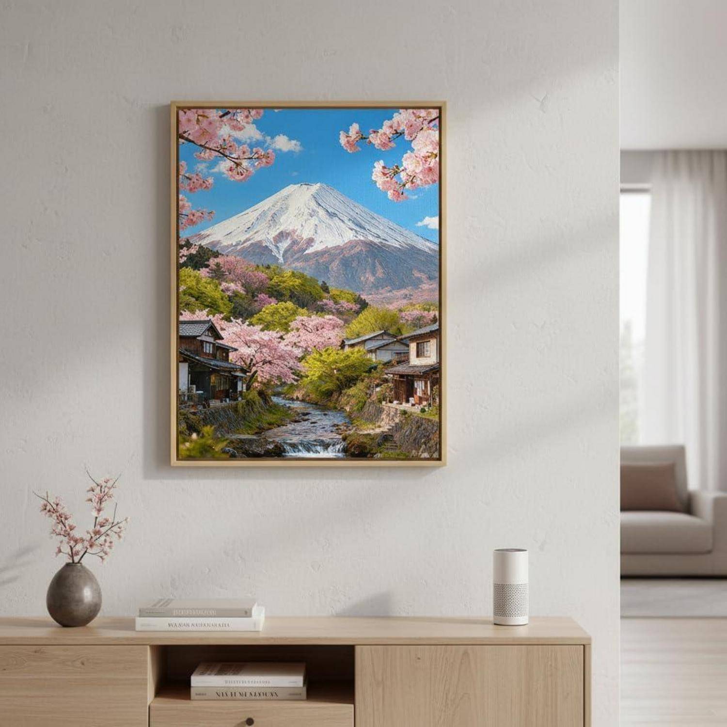 Gerahmter Landschaftsdruck des Berges Fuji mit Kirschblüten über einem Dorf, hängend an einer Wohnzimmerwand über einer Holzkonsole.