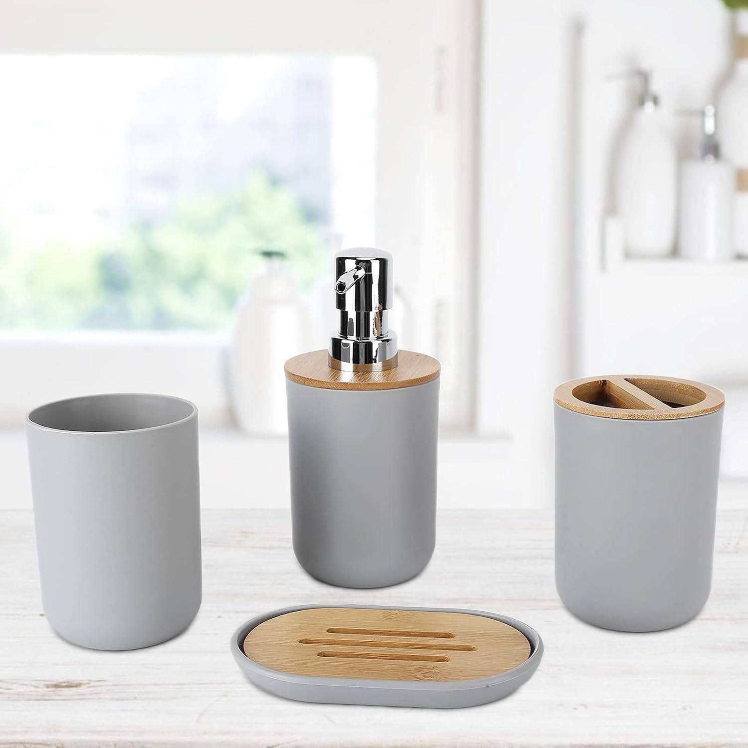 Graues Badezimmeraccessoire-Set mit Seifenspender, Becher, Zahnbürstenhalter und Tablett, jeweils mit Bambusdeckeln, auf einer weißen Arbeitsplatte.