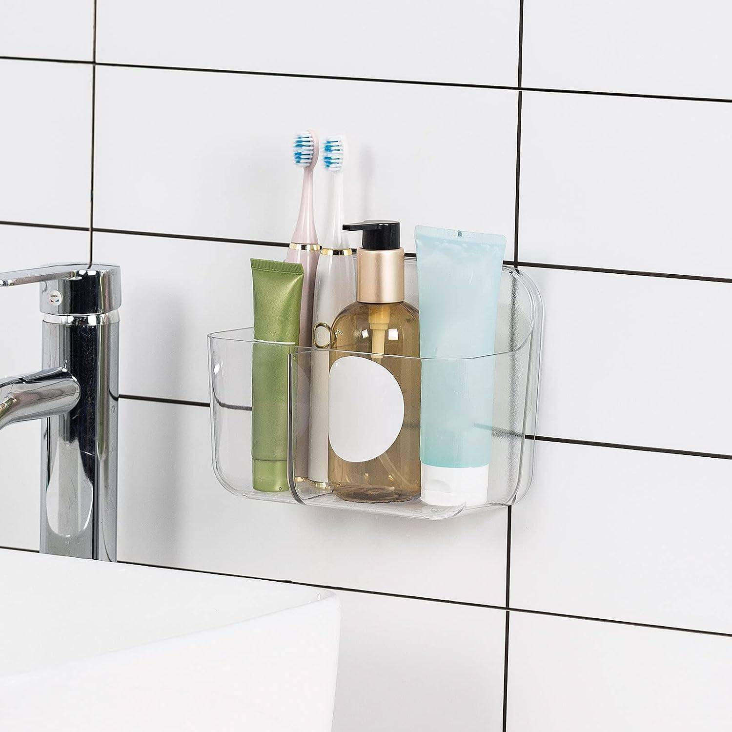 Klare wandmontierte Badezimmerorganizer mit zwei Zahnbürsten und drei Toilettenartikelfläschchen neben einem Waschbecken und Wasserhahn.