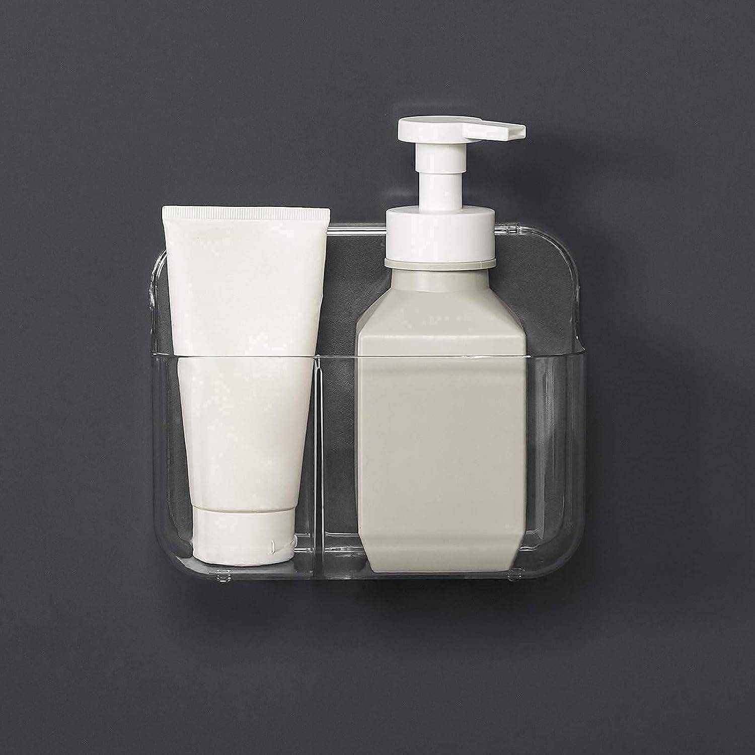 Transparenter, an der Wand montierter Badezimmerorganizer, der eine weiße Tube und einen Pumpspender auf dunklem Hintergrund hält.
