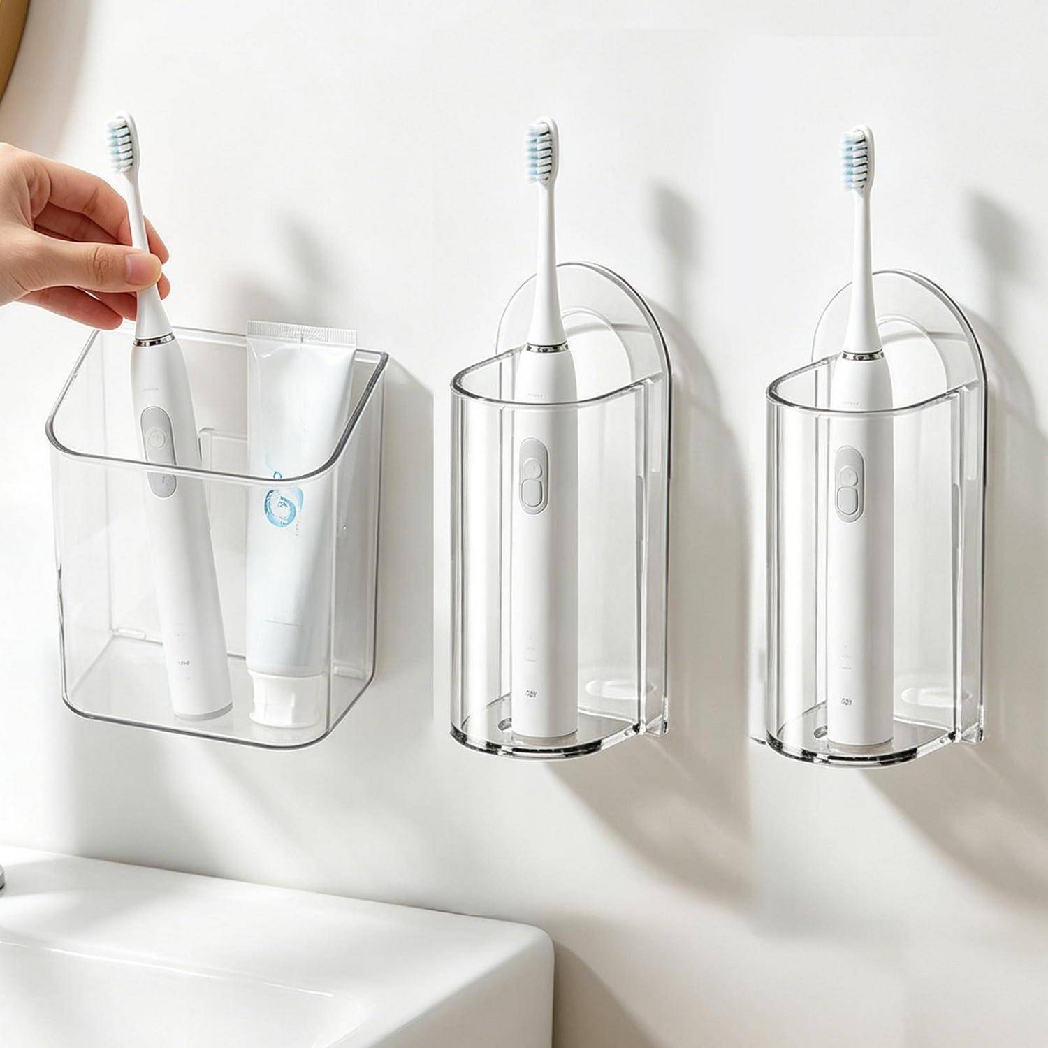 Wandmontierte transparente Zahnbürstenhalter zur Aufbewahrung von elektrischen Zahnbürsten und Zahnpasta; einer wird von einer Hand angehoben.