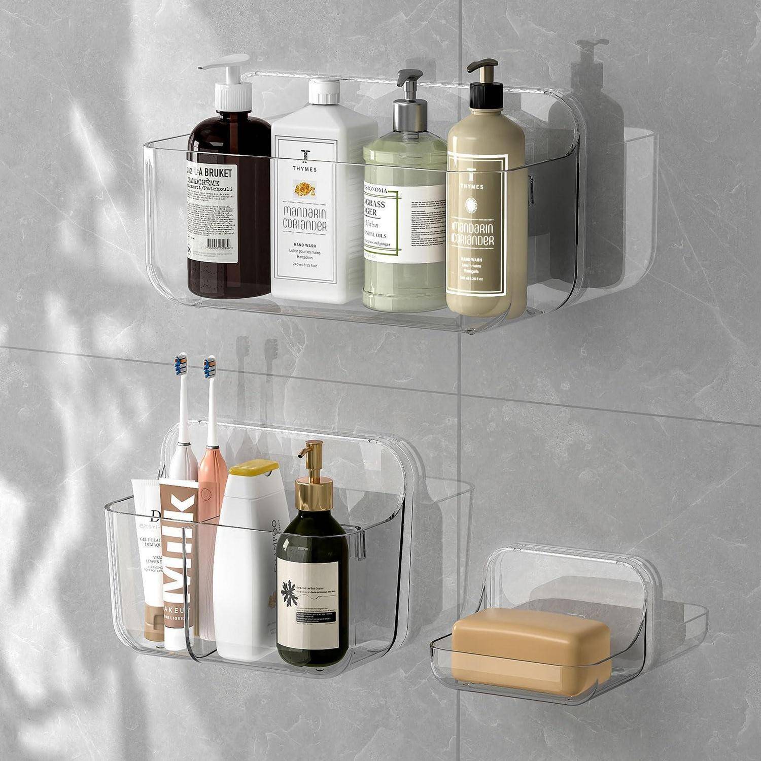 Transparente, an der Wand montierte Badezimmerorganizer mit Shampoo- und Conditioner-Flaschen, Zahnbürsten, einem Seifenspender und einer Seife auf einer gefliesten Wand.