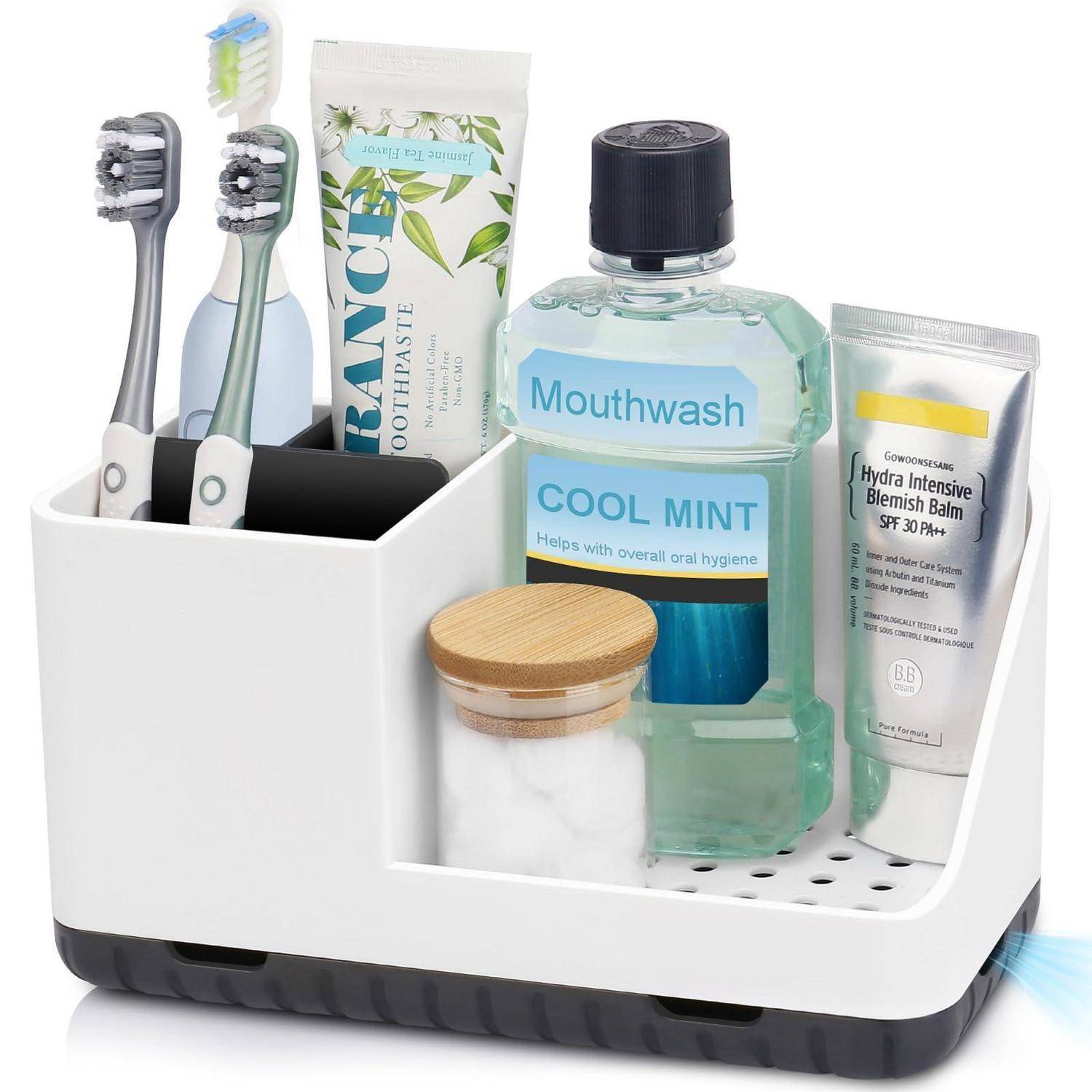 Badezimmer-Arbeitsplatte-Organizer, der zwei Zahnbürsten, Zahnpasta, Mundwasser, Hautpflegecreme, Wattepads und ein Glas mit einer kleinen Fanbasis hält.