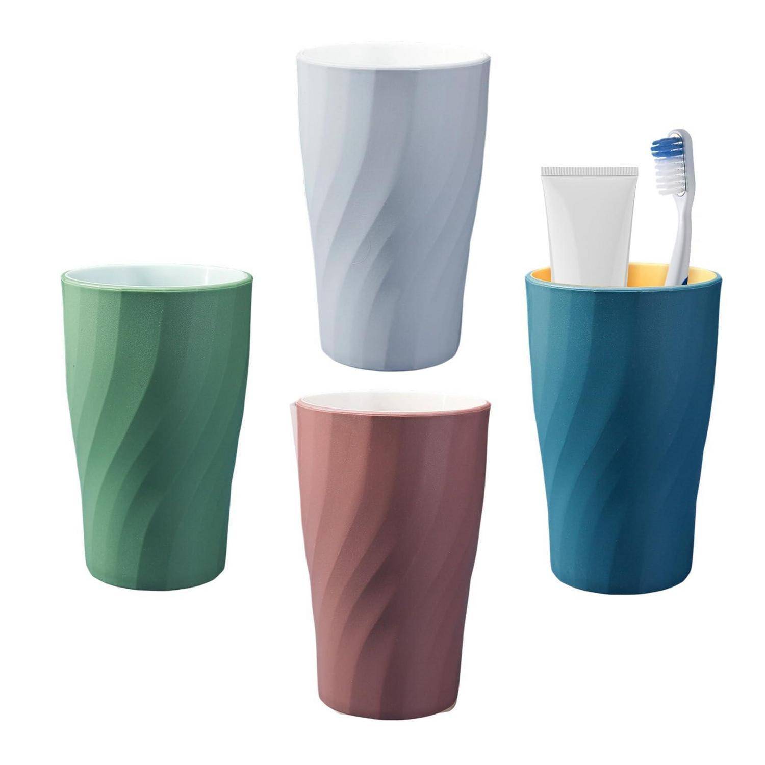 Vier strukturierte Badezimmergläser in Grün, Grau, Rosa und Blau; das blaue Glas enthält eine Zahnbürste und eine Zahnpastatube.