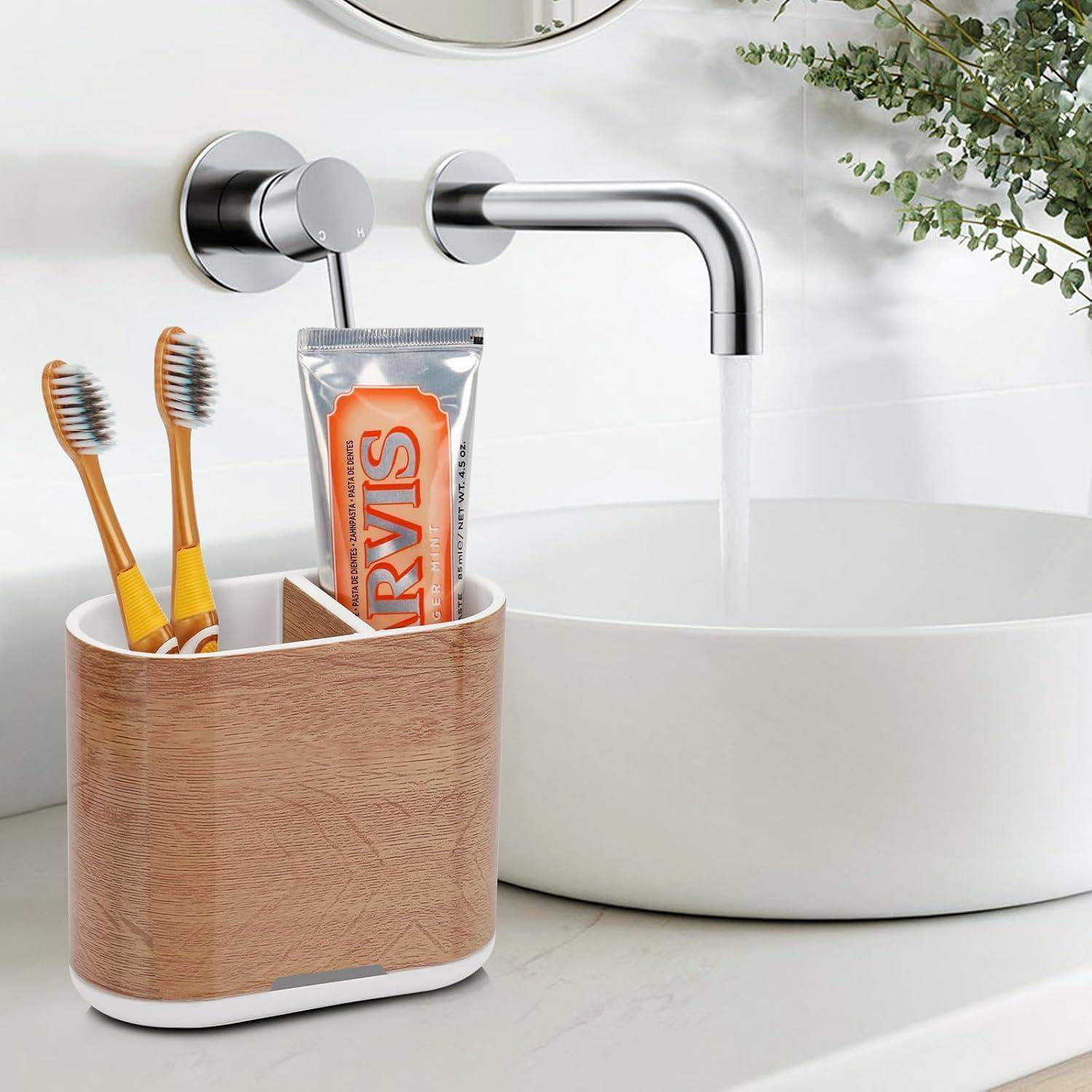 Badezimmerspüle mit laufendem Wasserhahn, weißem Becken und einer Ablage auf der Arbeitsplatte, die zwei Zahnbürsten und eine Zahnpastatube hält.