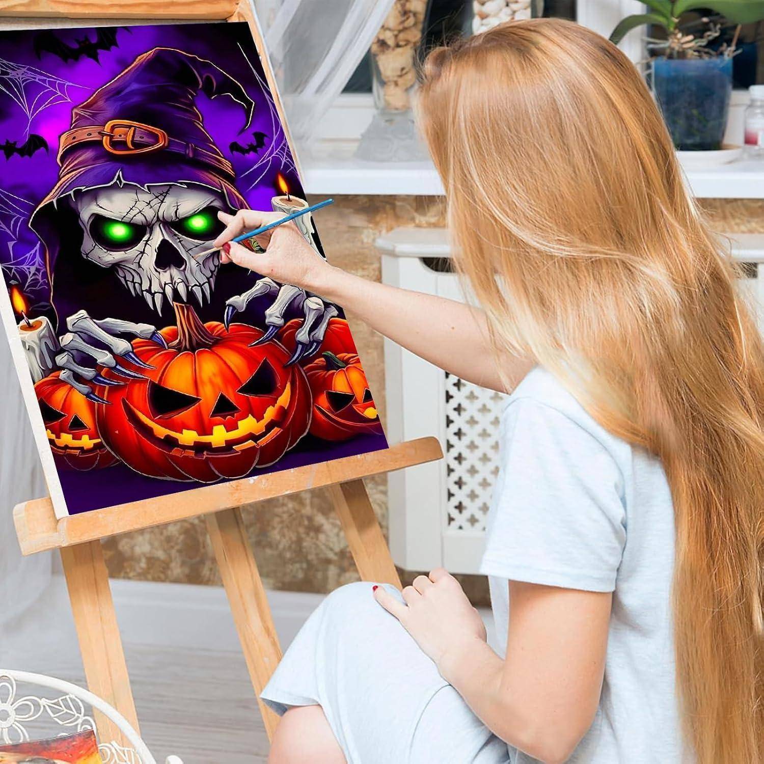 Mädchen malt eine Halloween-Szene mit einer schädelhäutigen Hexe mit leuchtend grünen Augen auf einem Kürbis auf einer Staffelei in einem Innenraum.