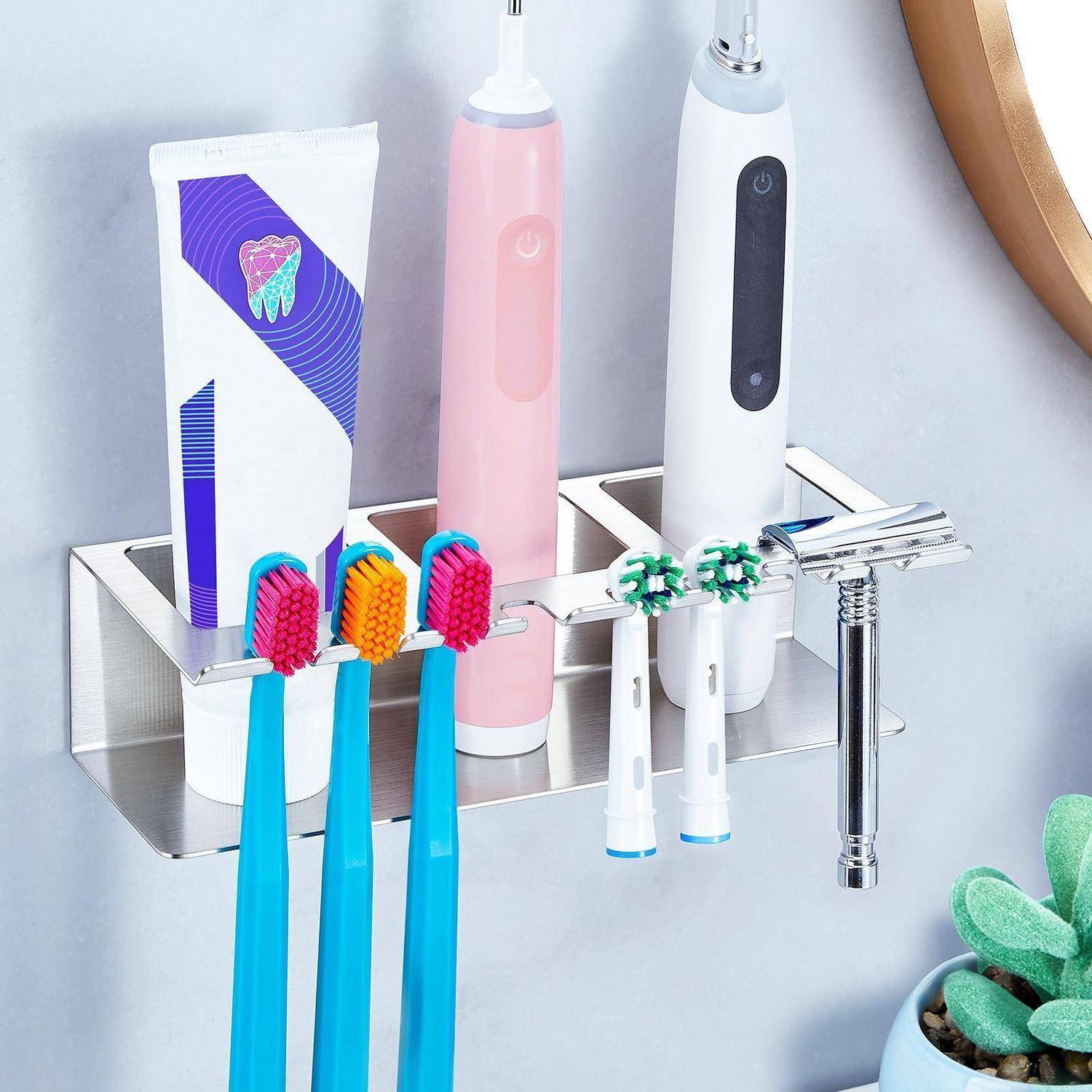 An der Wand montierter Badezimmerorganizer, der auf einem silbernen Regal elektrische Zahnbürsten, Zahnpasta und einen Rasierer hält.