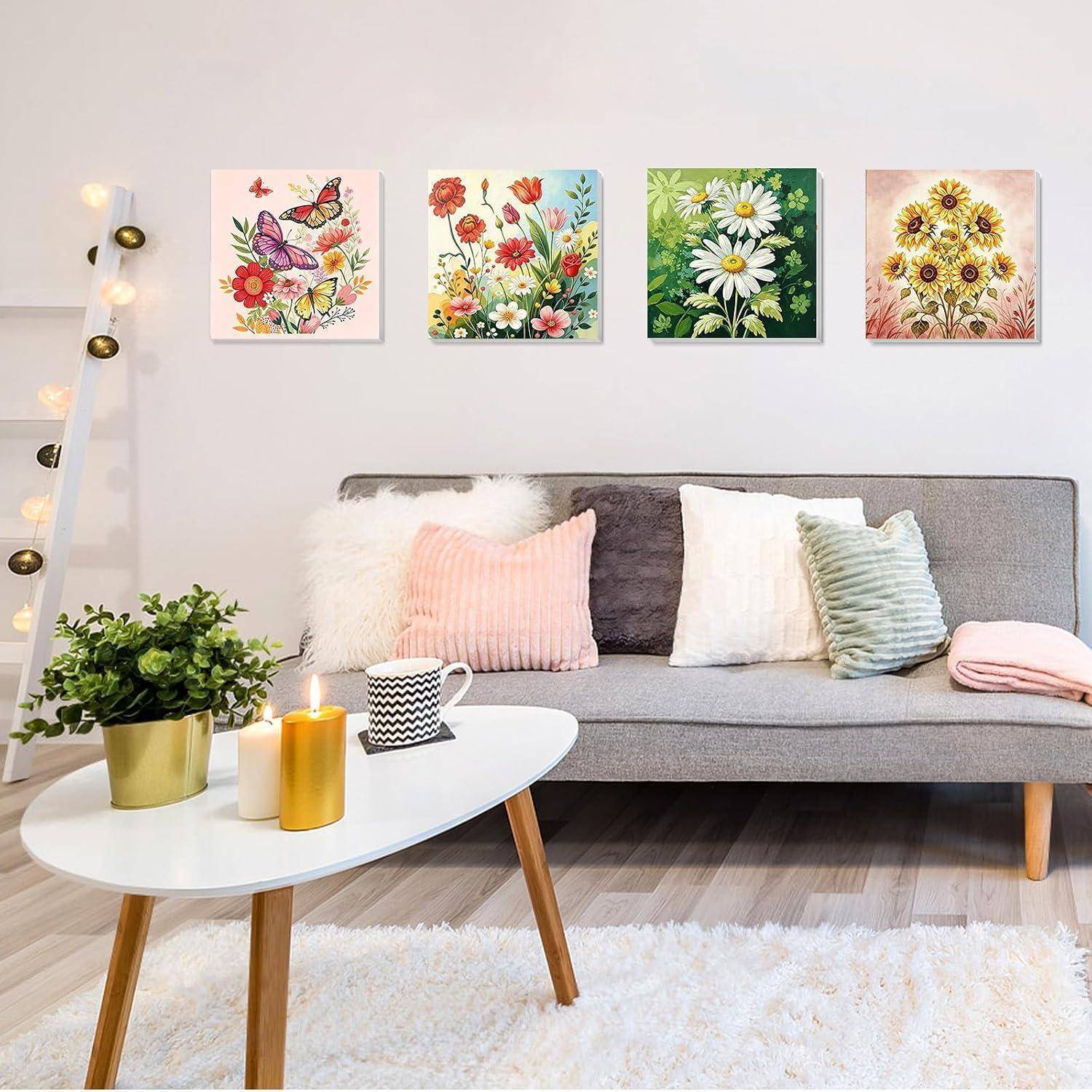 Modernes Wohnzimmer mit grauem Sofa, weißem Couchtisch, Kerzen, Pflanze und vier floralen Wanddrucken über dem Sofa.