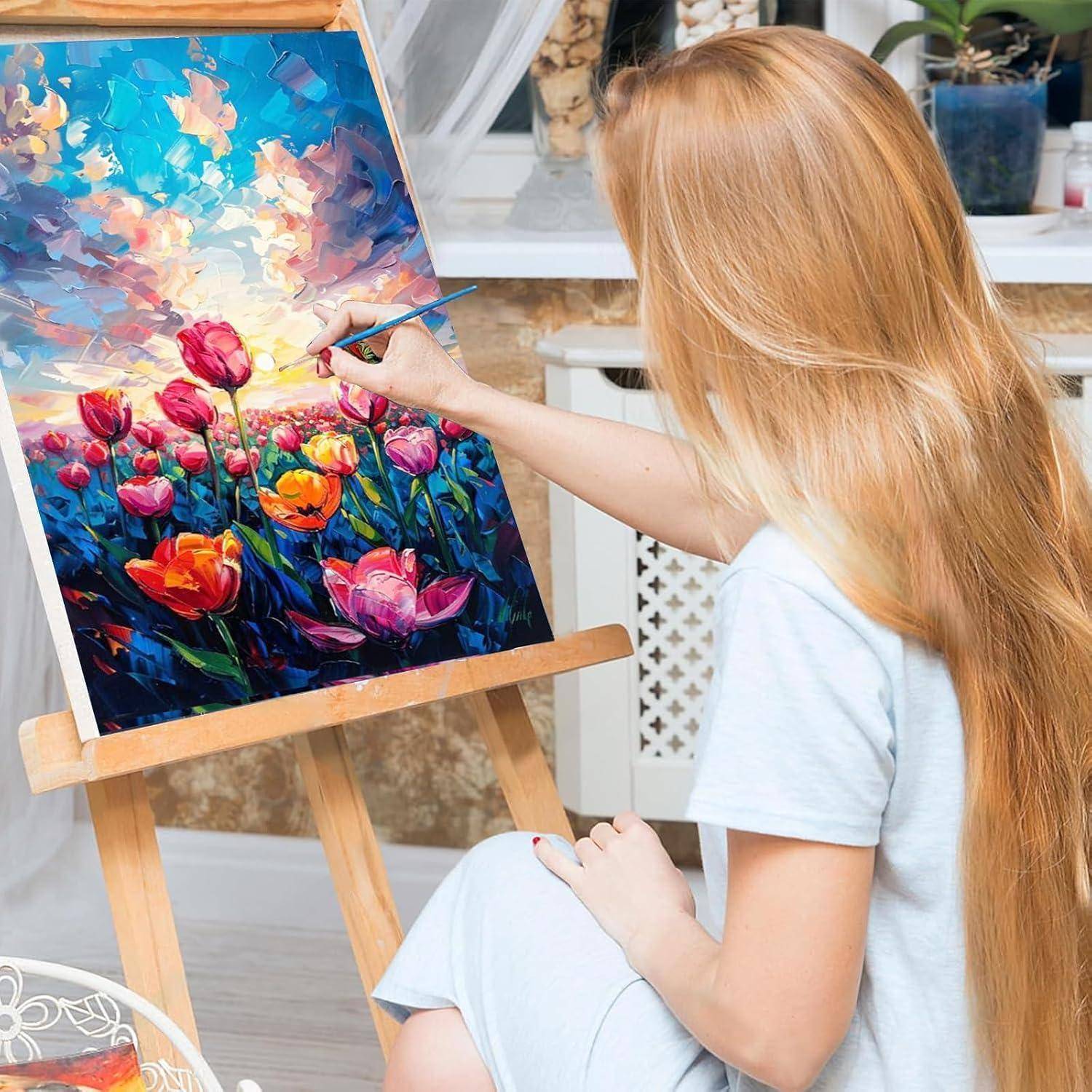 Blonde Frau, die einen farbenfrohen Blumenstrauß auf einer Leinwand an einer Staffelei in Innenräumen malt.