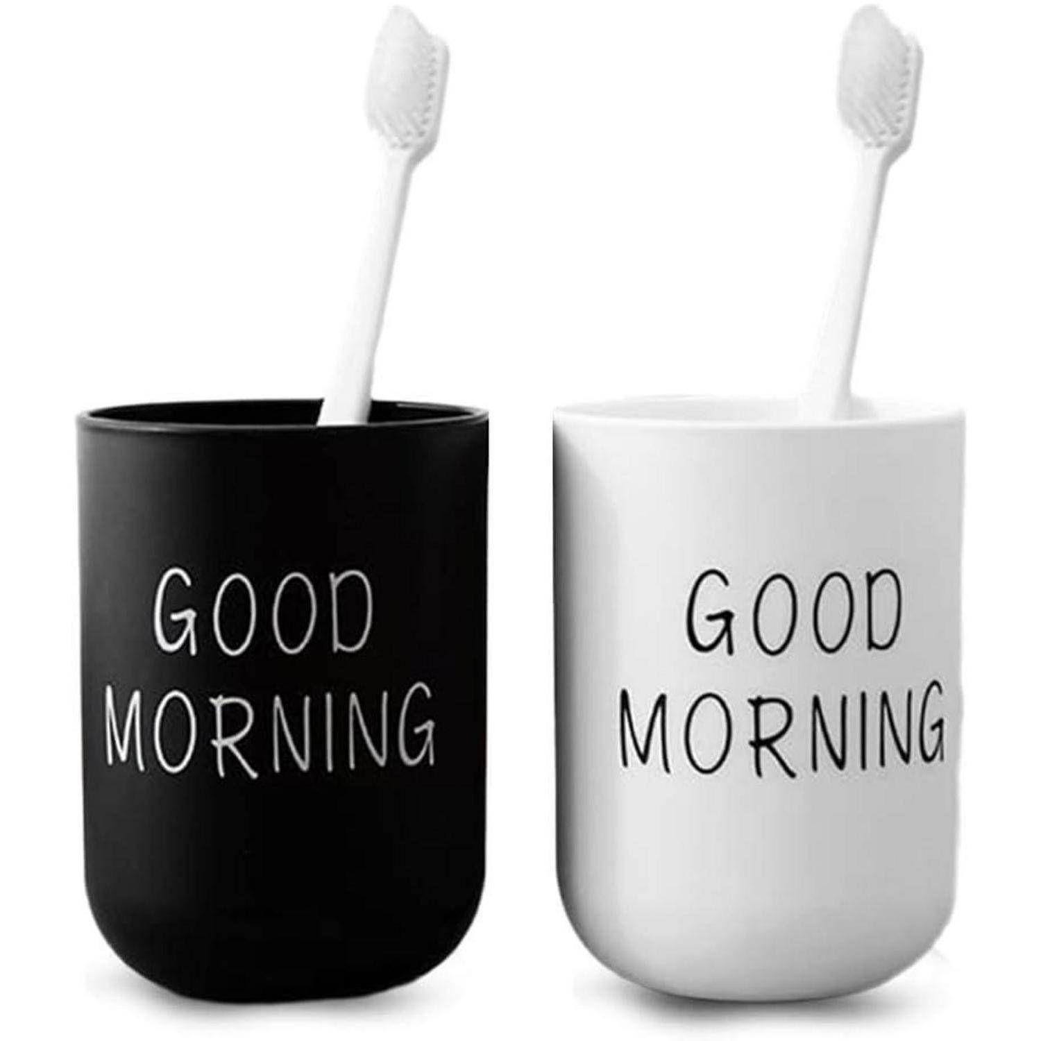 Zwei Zahnbürsten in schwarzen und weißen Bechern mit der Aufschrift „GUTEN MORGEN