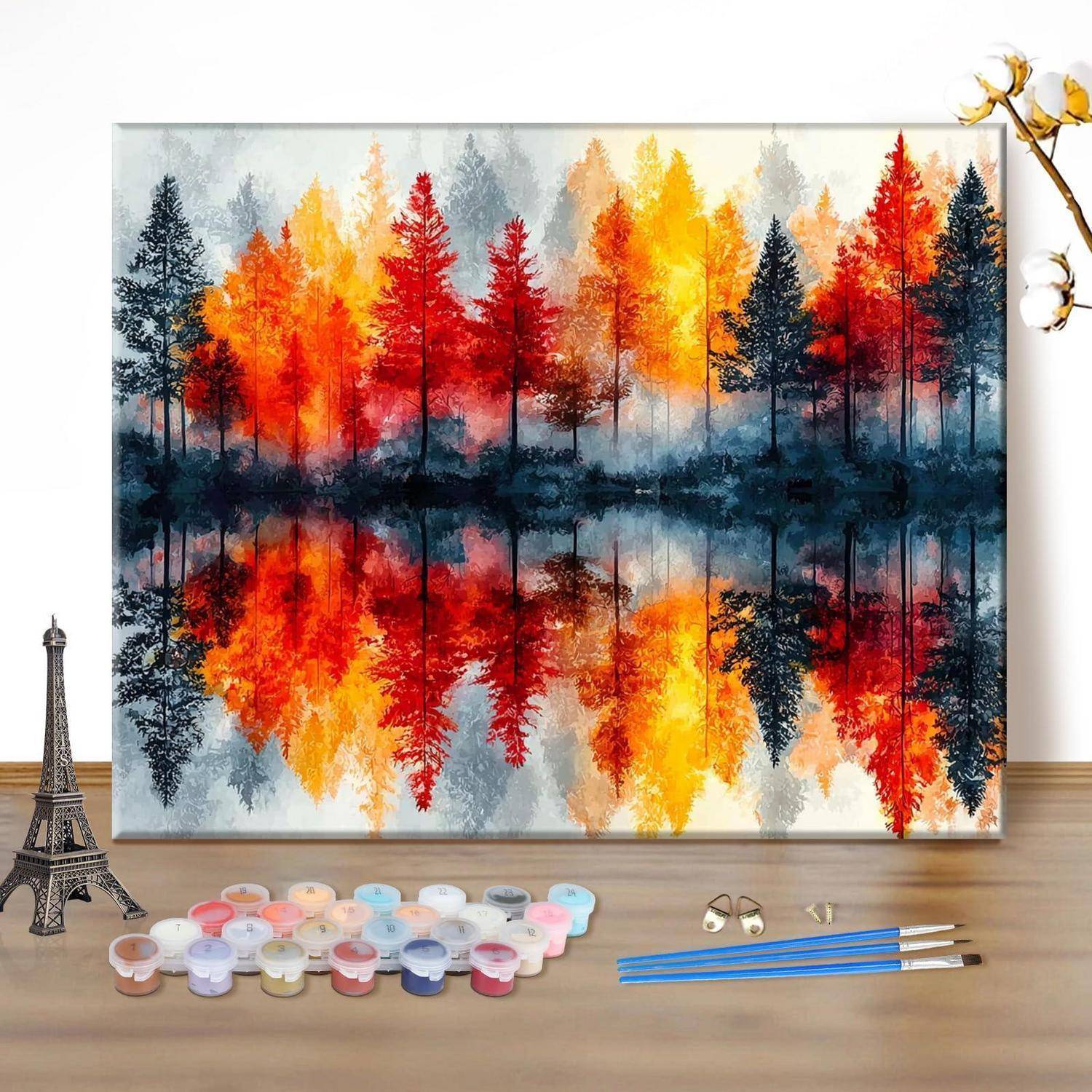 Fertiggestelltes Waldgemälde mit leuchtend roten, orangefarbenen und gelben Bäumen, die sich im Wasser spiegeln, dargestellt als Kunstset mit Farben und Pinseln