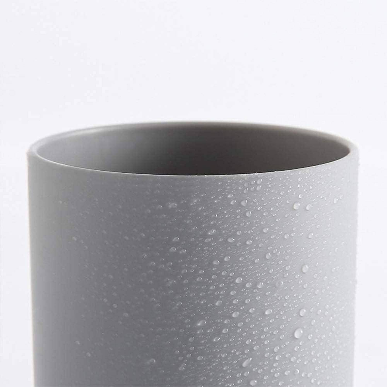 Grauer zylindrischer Becher mit matter Oberfläche und Wassertropfen auf der Oberfläche, vor weißem Hintergrund dargestellt.