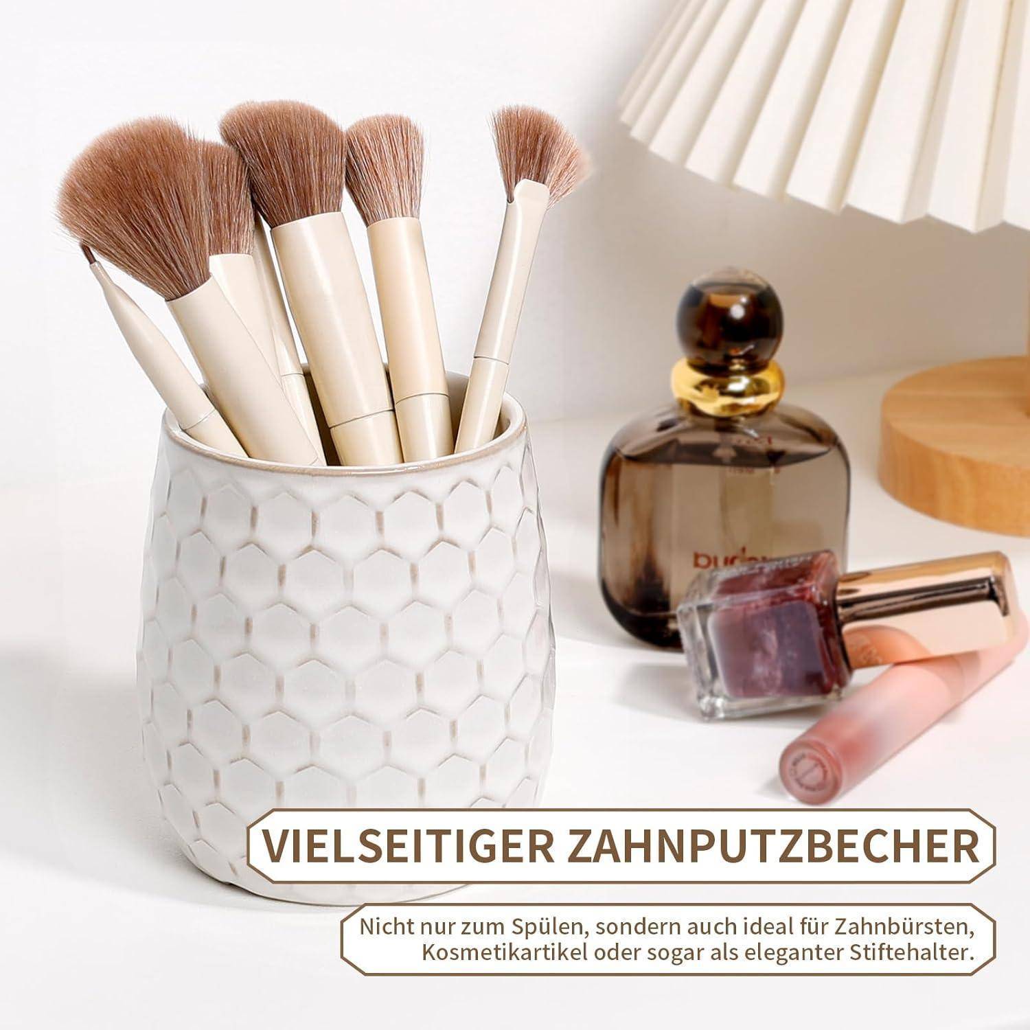 Weiße Becher mit Sechseck-Muster, der Makeup-Pinsel neben Parfümflaschen und einer Lampe hält, auf Deutsch als vielseitiger Zahnbürscher-Becher gekennzeichnet.