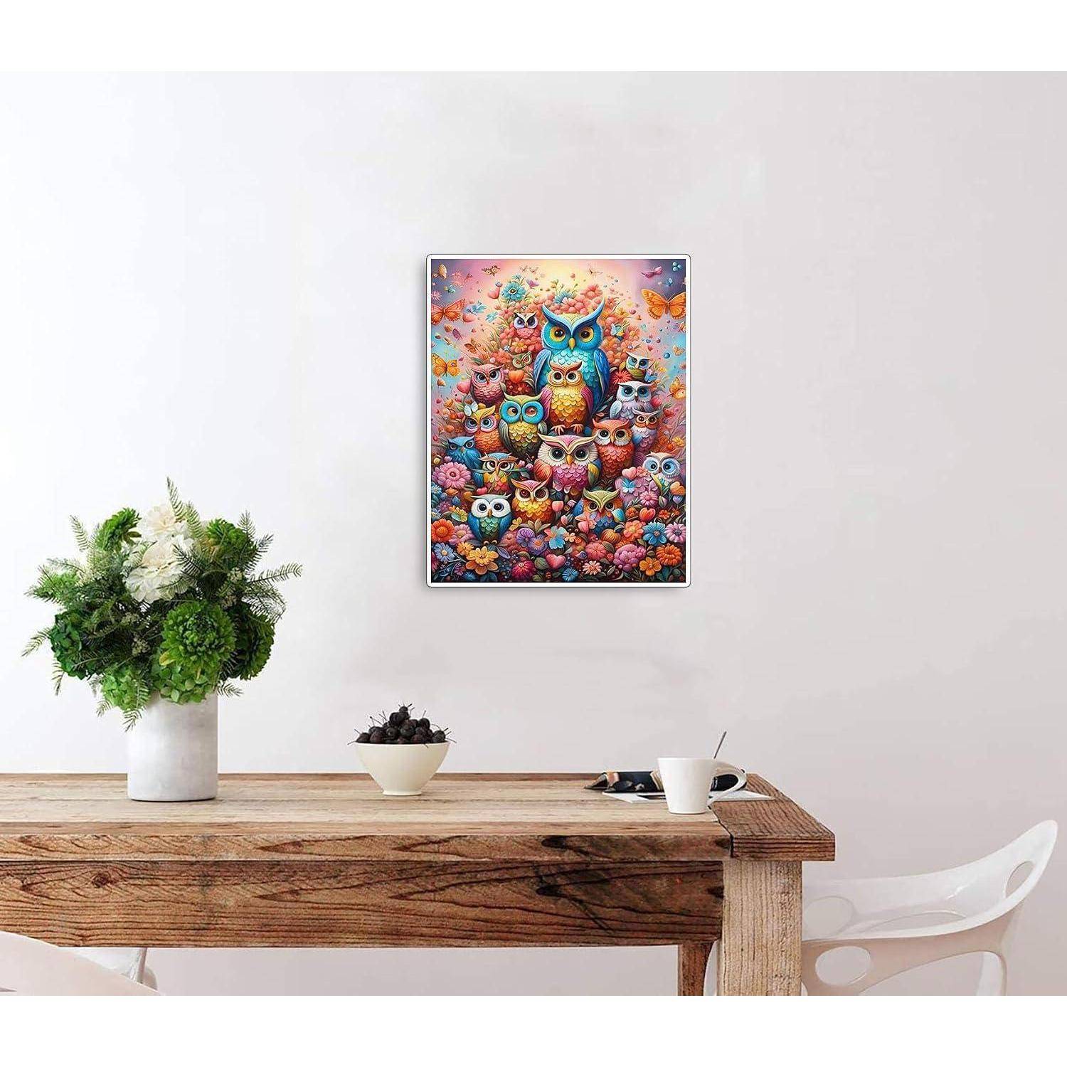 Ein buntes Eulen-Plakat hängt an einer weißen Wand über einem rustikalen Holztisch mit Pflanzen und einer Tasse in einem minimalistischen Zimmer.