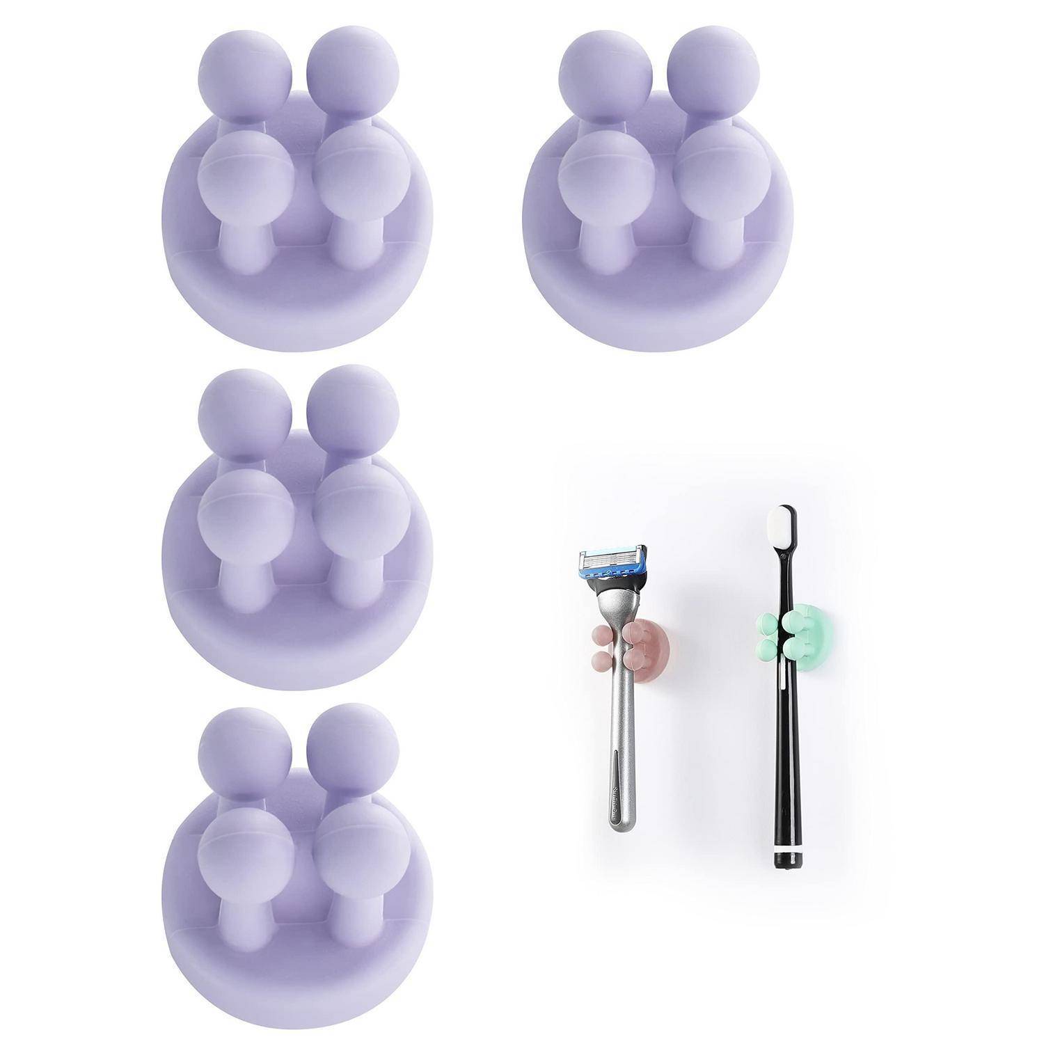Violette Saugnäpfe-Wandhaken halten Zahnbürsten und einen Rasierer auf weißem Hintergrund.