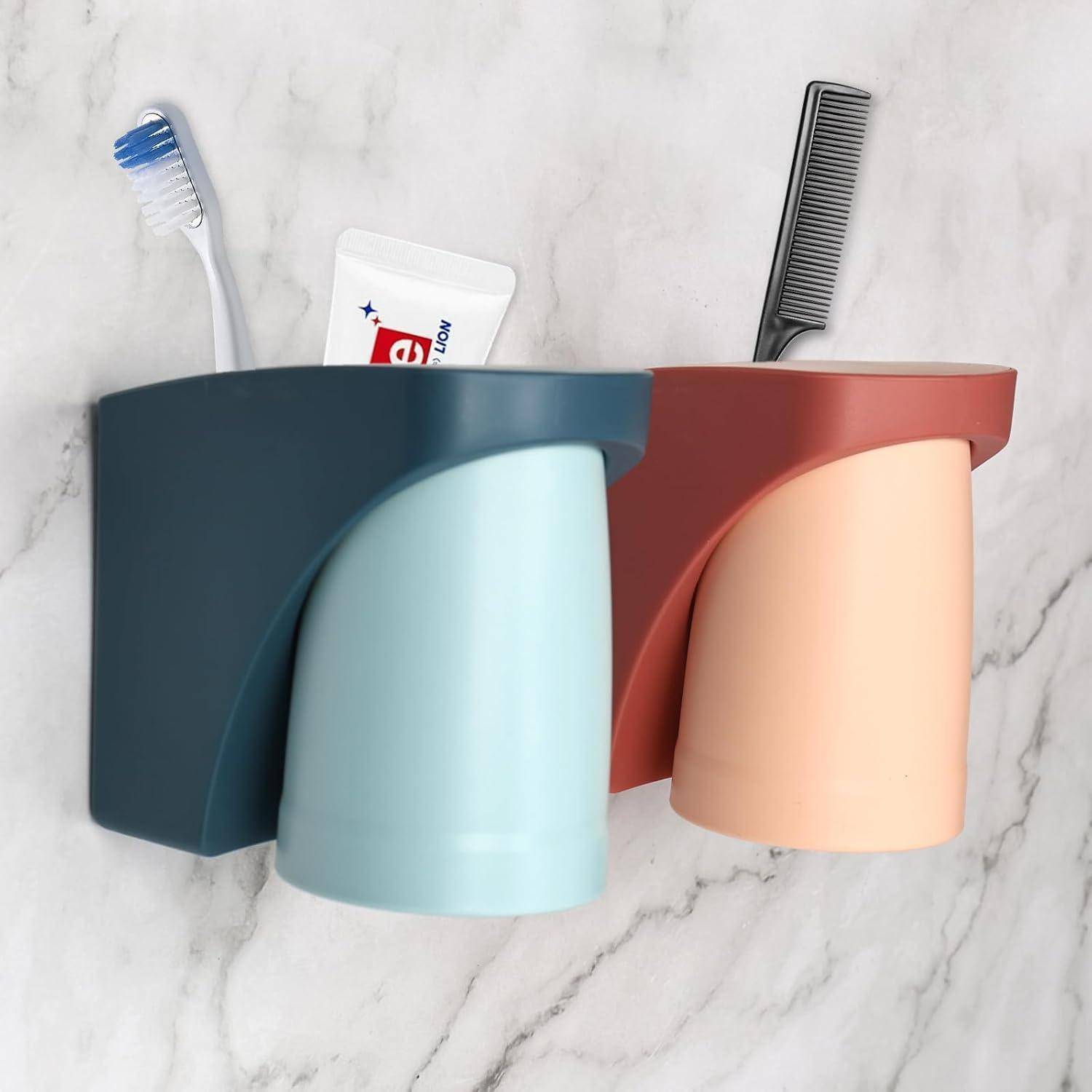 Zwei wandmontierte Badezimmerorganizer mit Bechern halten Zahnbürste, Zahnpasta und Kamm an einer Marmor Wand.
