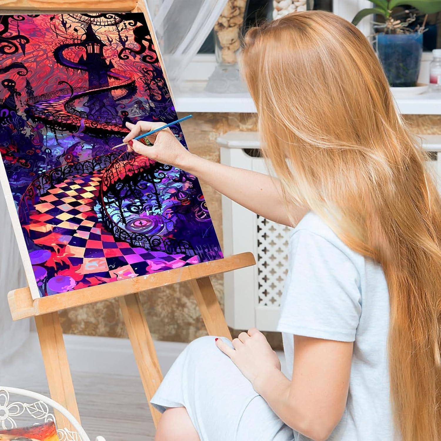 Eine Frau malt ein farbiges surreales Kunstwerk auf einer Leinwand an einer Staffelei in einem hellen Atelier.