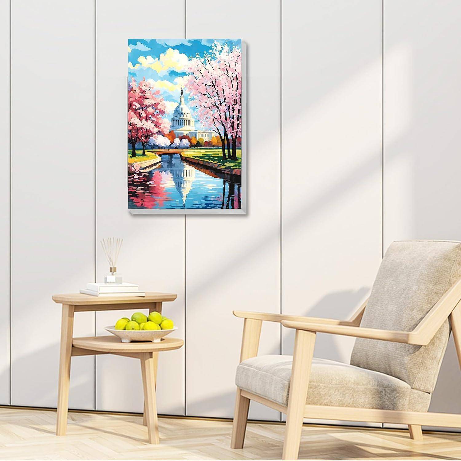 Gerahmtes Gemälde des US-Kapitols mit Kirschblüten, die sich in einem Kanal spiegeln, hängend über einem kleinen Beistelltisch und einem Loungesessel in einem hellen Raum.