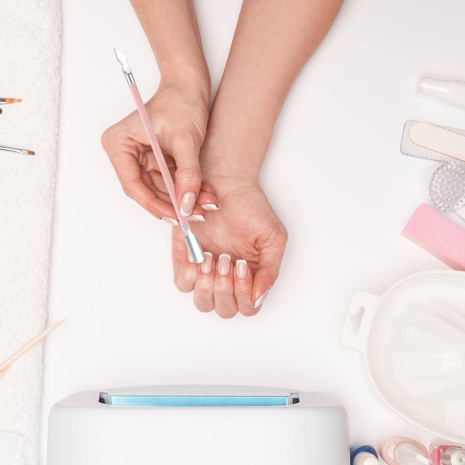 Hände, die eine Maniküre erhalten, während ein Nagelwerkzeug einen Fingernagel auf einem weißen Tisch reinigt und formt, mit Maniküre-Artikeln in der Nähe.