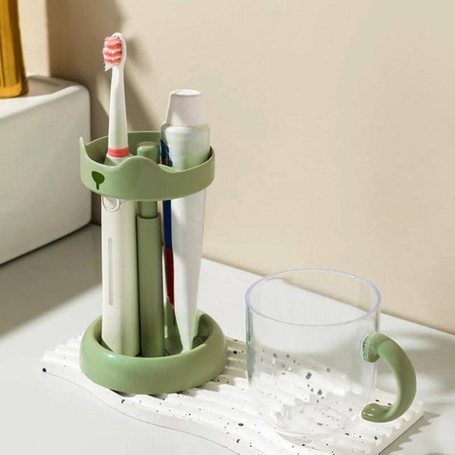 Grüner Arbeitsplatzorganizer mit Zahnbürsten und Toilettenartikeln neben einer durchsichtigen Tasse auf einer weißen Spülbeckenmatte.