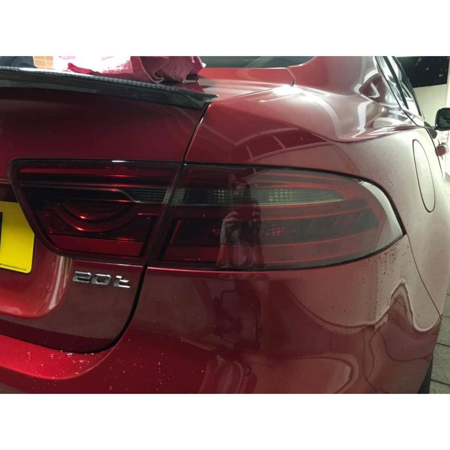 Hinterseite einer roten Tesla 20d Limousine, die das linke Rücklicht, den Kofferraum und das hintere Badge in einer Garage zeigt.