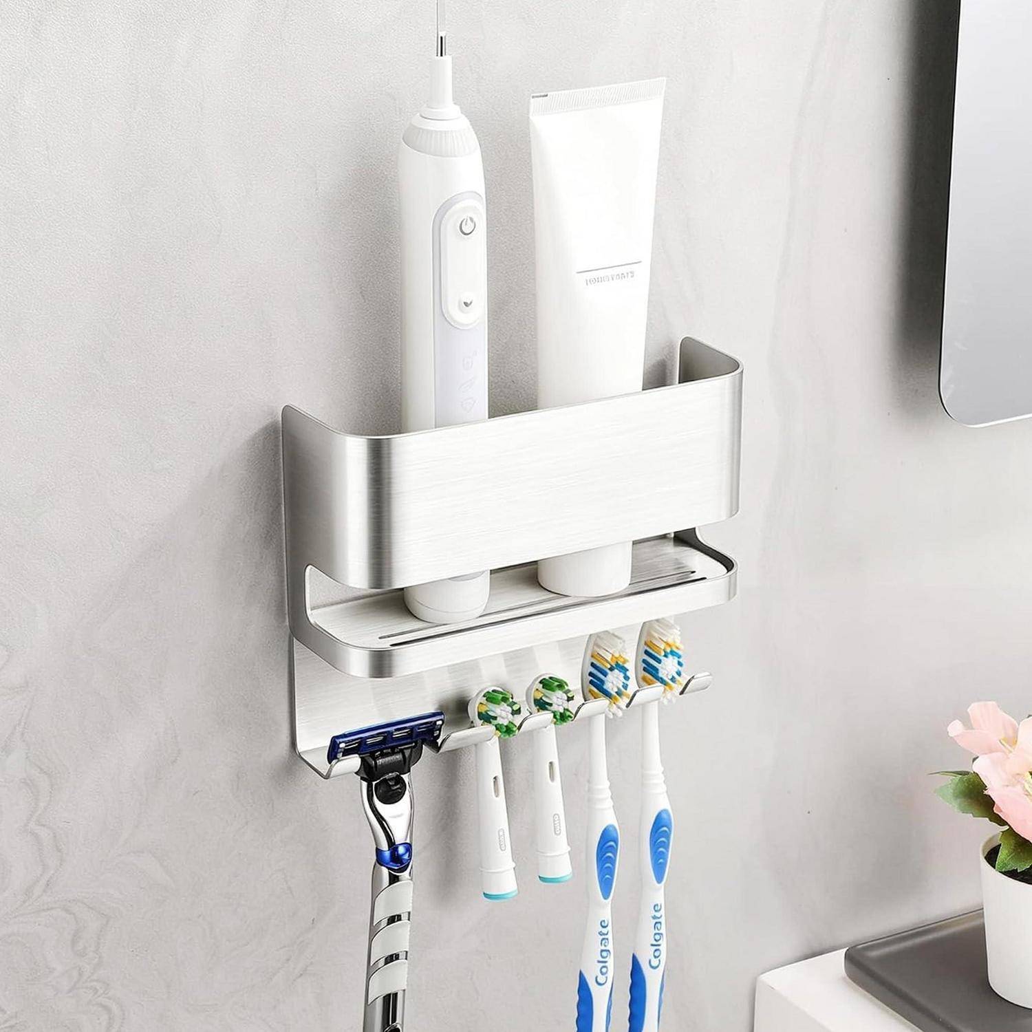 An der Wand montierter Badezimmerorganizer, der eine elektrische Zahnbürste, Zahnpastatuben, Rasierer und Zahnbürsten neben einem Waschbecken hält.