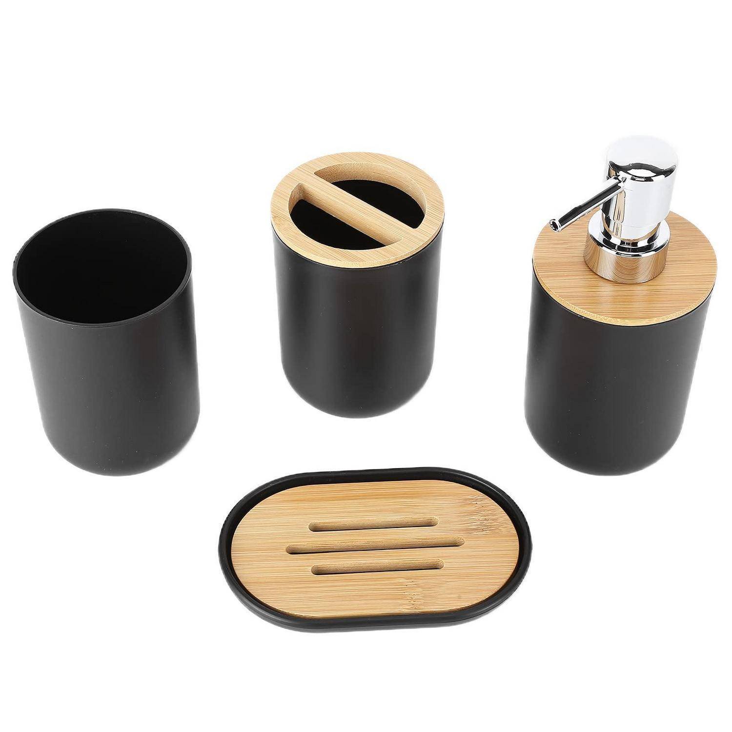 Vier schwarze Badezimmeraccessoires mit Bambusakzenten: ein Becher, ein Behälter mit Deckel, ein Seifenspender und eine ovale Seifenschale auf weißem Hintergrund.