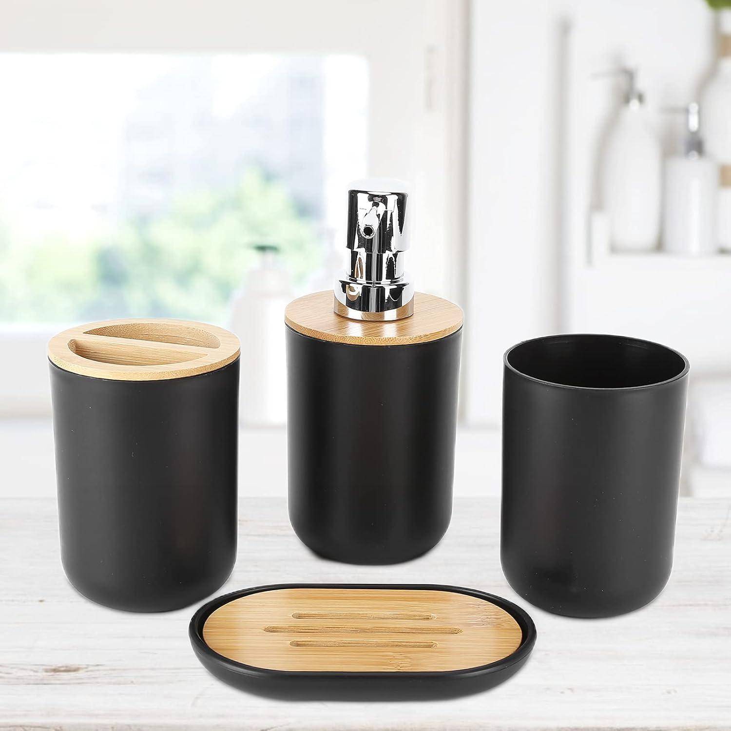 Schwarzes Badezimmer-Set mit Bambus-Akzenten: Seifenspender, Behälter mit Deckel, Becher und ovales Tablett auf einer hellen Oberfläche.