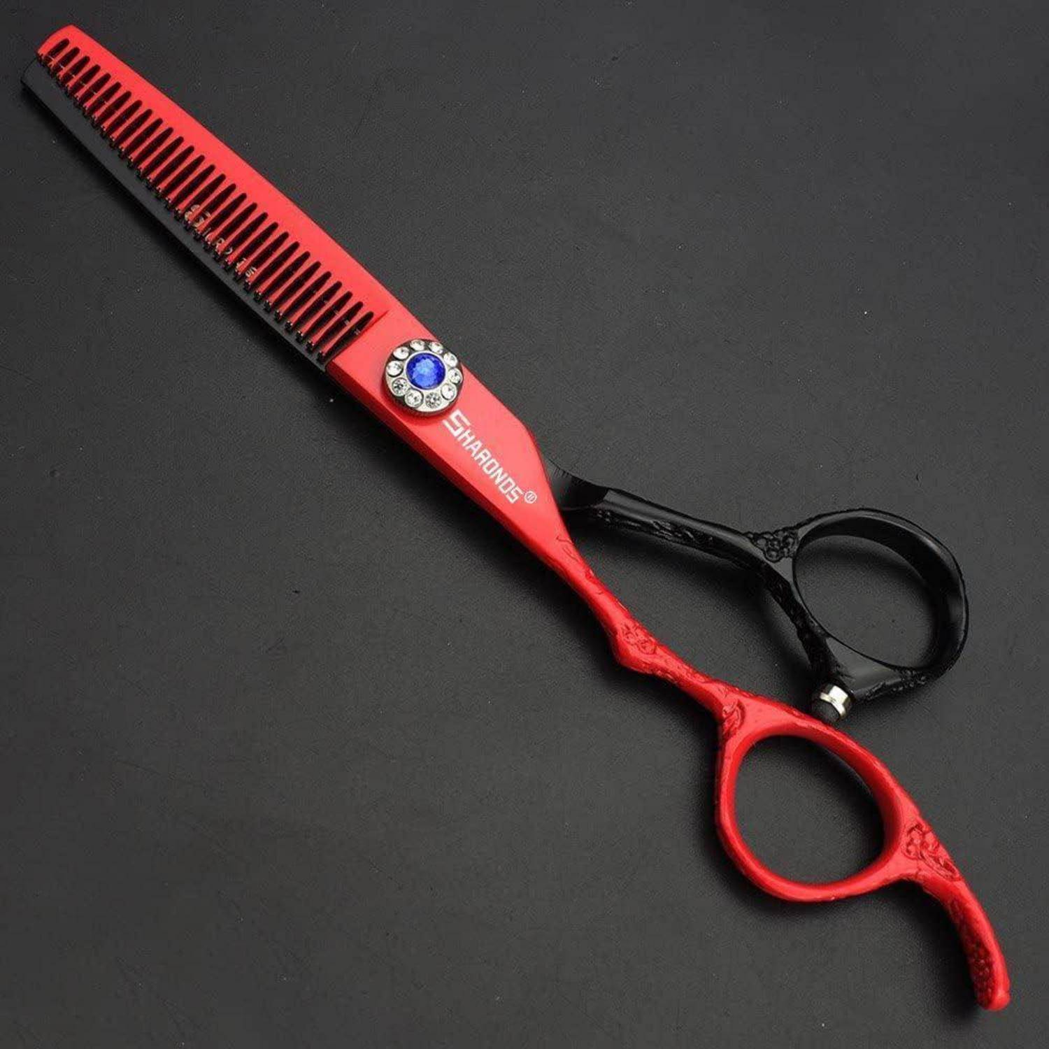 Rote und schwarze Haarschneidescheren mit Kammklinge und Fingerringen auf dunklem Hintergrund.