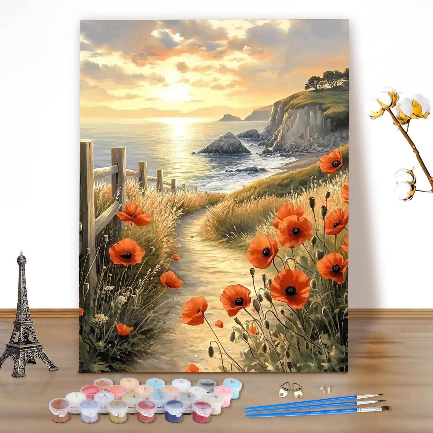Bemalte Meeresklippenlandschaft und Mohnfeld bei Sonnenuntergang, auf einer Staffelei über Kunstzubehör auf einem Tisch ausgestellt.