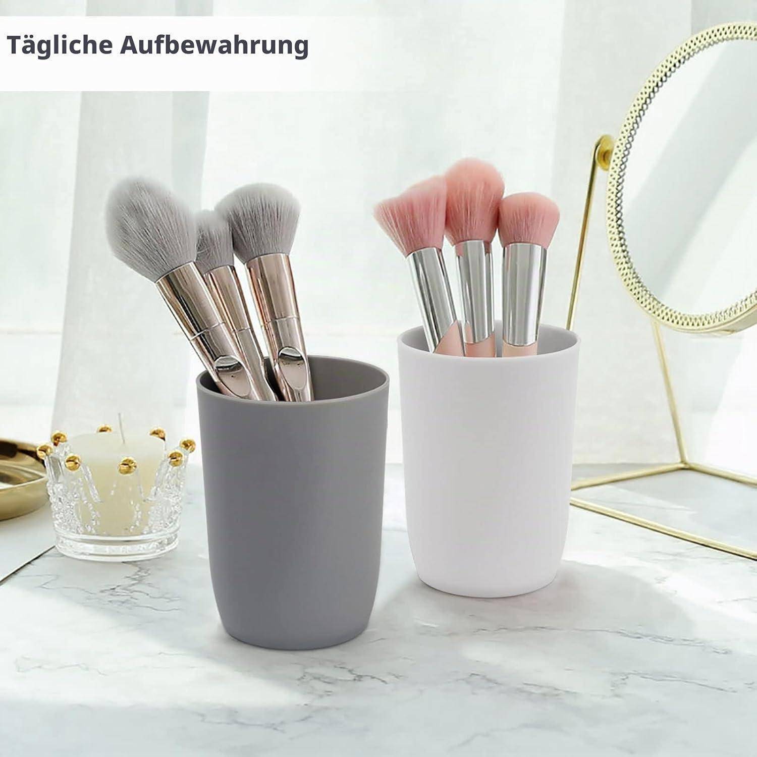 Zwei Tassen halten Makeup-Pinsel auf einem Frisiertisch; deutscher Text liest „Tägliche Aufbewahrung