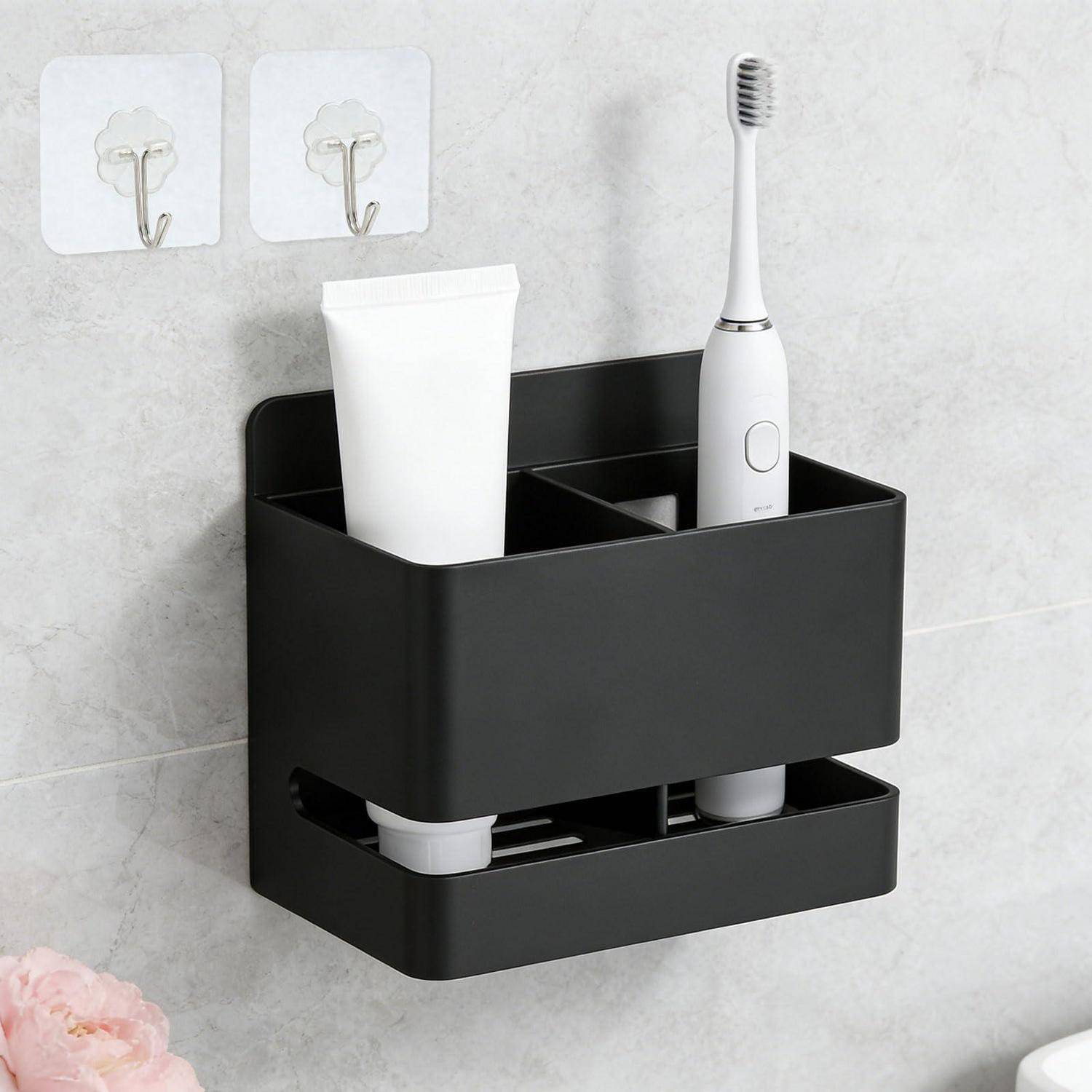 Schwarz an der Wand montierter Badezimmerorganizer, der eine Zahnbürste und Zahnpasta hält, mit zwei Klebehaken darüber.