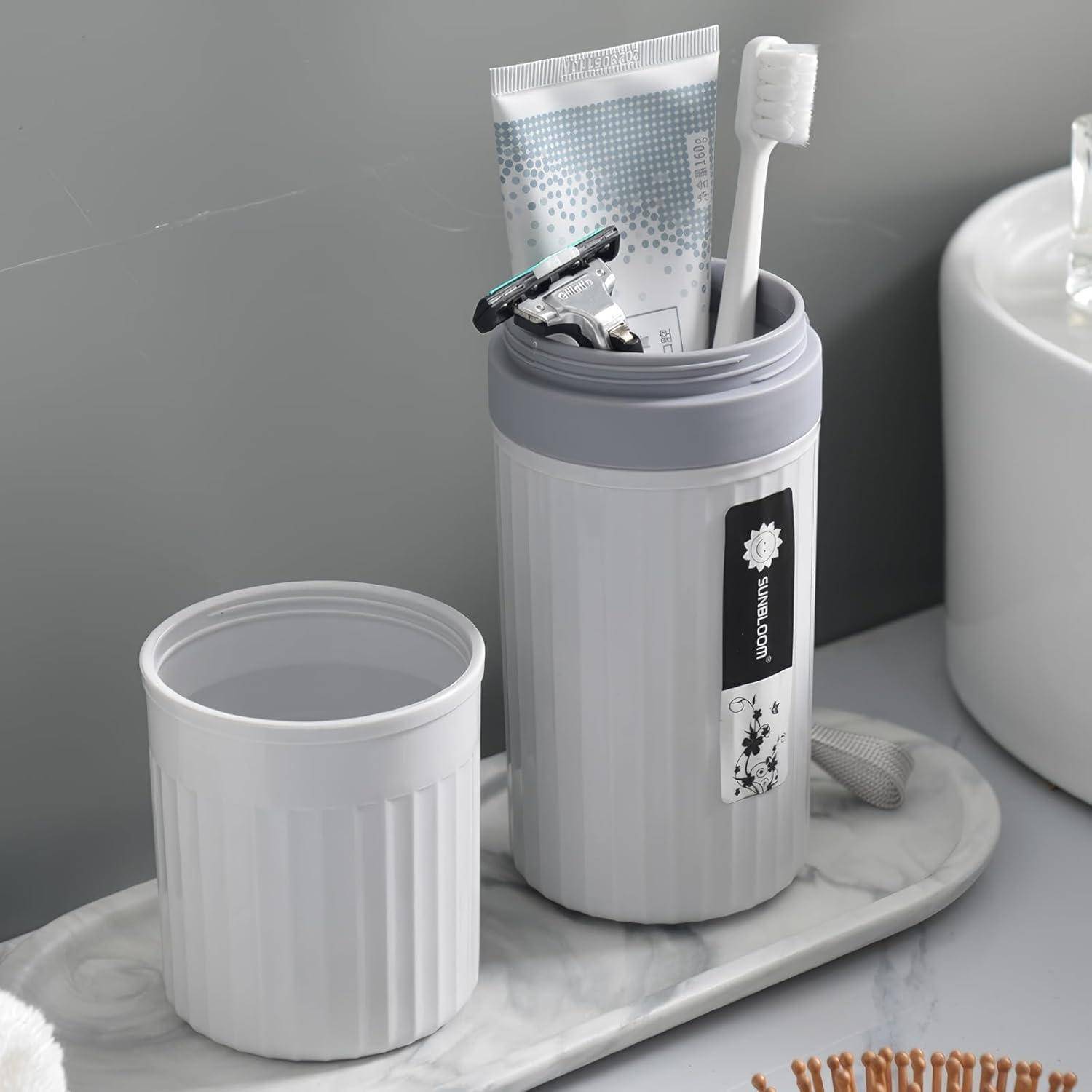 Weißes Badezimmer-Organizer-Set: ein Zahnbürstenbecher mit Deckel, der eine Zahnbürste, Zahnpasta und einen Rasierer enthält, neben einem passenden leeren Becher auf einem Marmortablett.