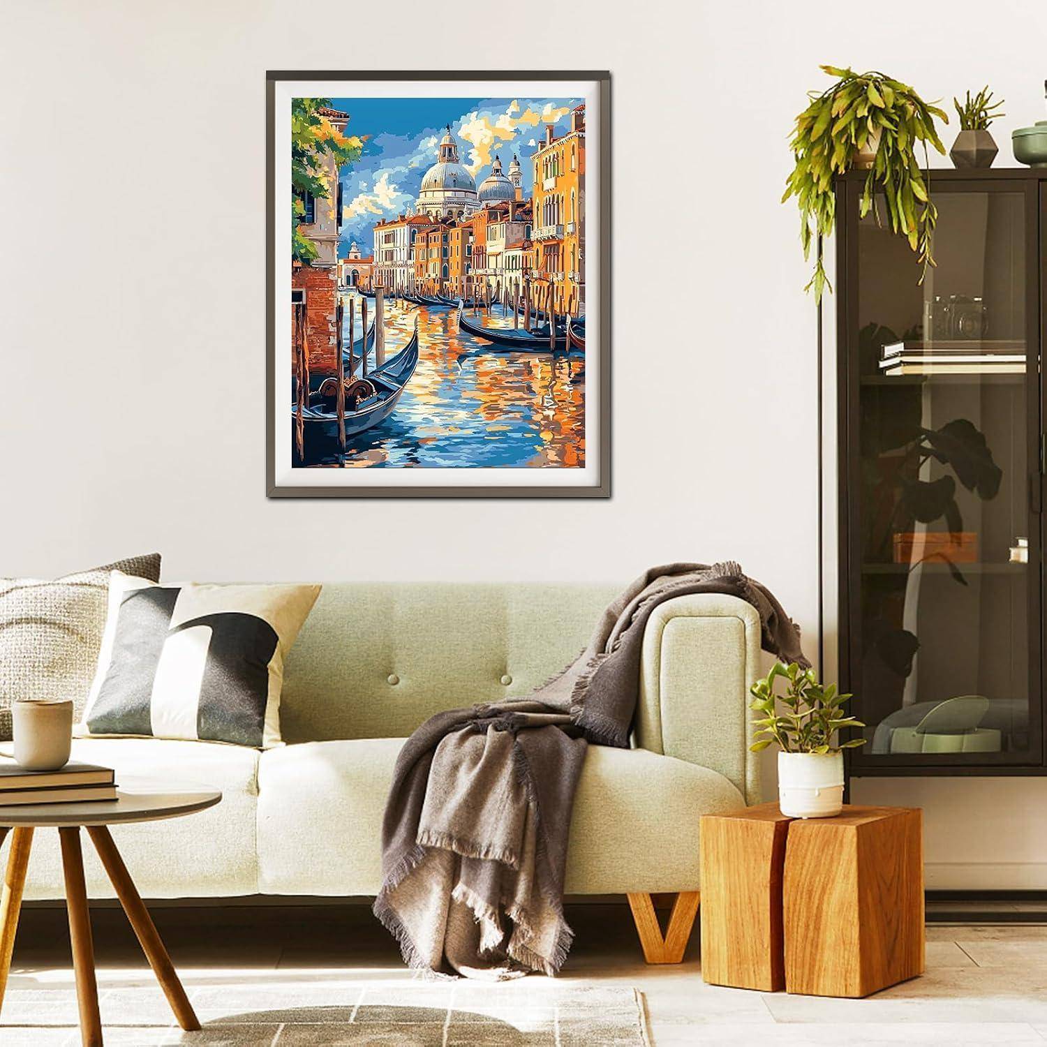 Helles modernes Wohnzimmer mit einem hellen Sofa, Kissen, Wurfdecke, Beistelltisch, Pflanzen, Schrank und einem gerahmten farbenfrohen Kanalgemälde an der Wand.