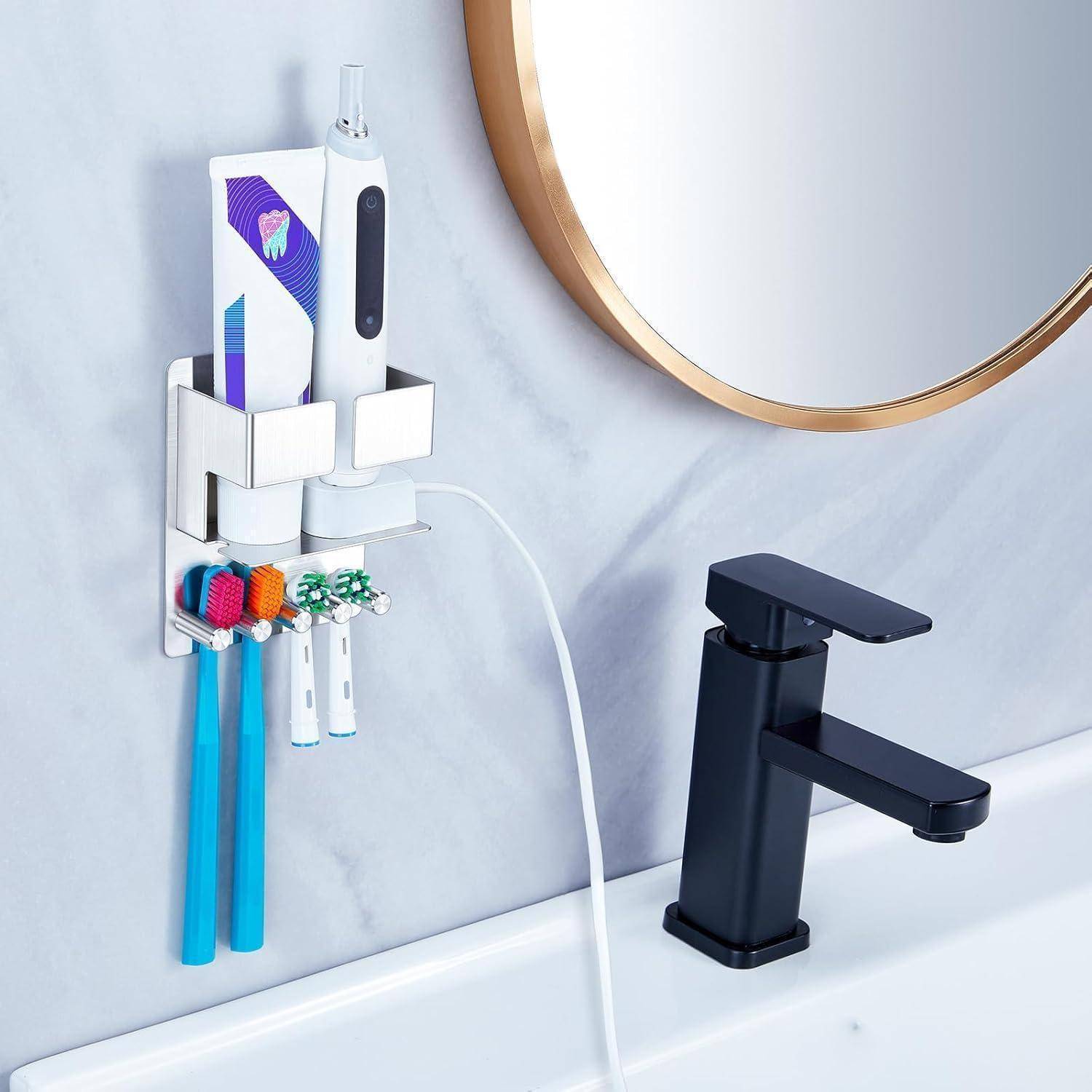 Wandmontierter Badezimmerhalter mit elektrischer Zahnbürste, Zahnpasta, Rasierer und Ladekabel neben einem Waschbecken und einer Armatur.