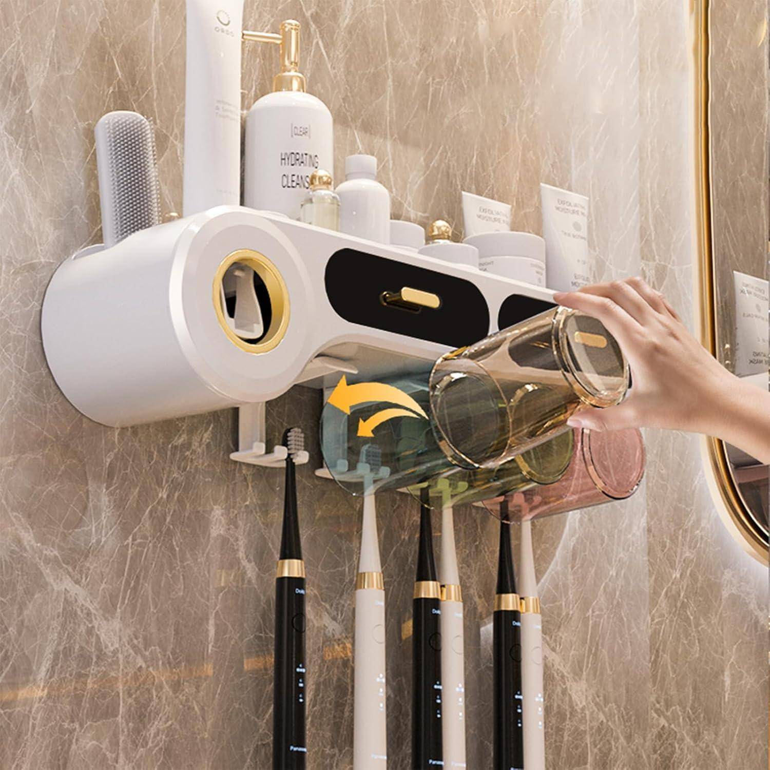 Eine Hand gießt Wasser aus einem Glas in einen an der Wand befestigten Badezimmerorganizer, der Zahnbürsten und Toilettenartikel enthält.