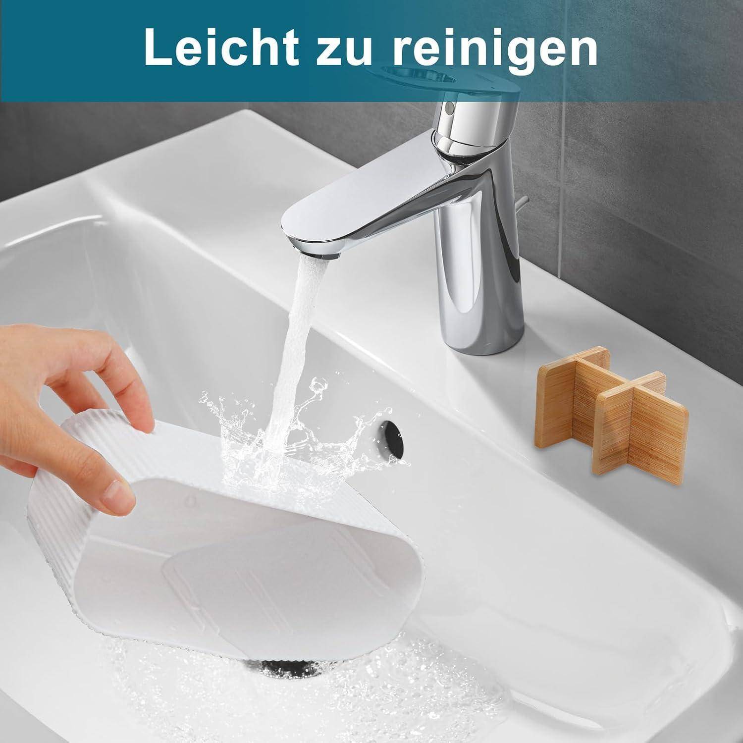Badezimmerbecken wird unter einem laufenden verchromten Wasserhahn gespült, mit dem deutschen Text „Leicht zu reinigen