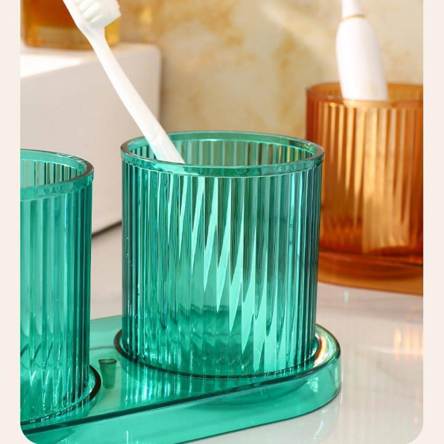 Teal-gerippter Badezimmerbecher mit einer weißen Zahnbürste, mit passenden Behältern in Bernstein- und Grüntönen auf einem Vanity-Tablett.