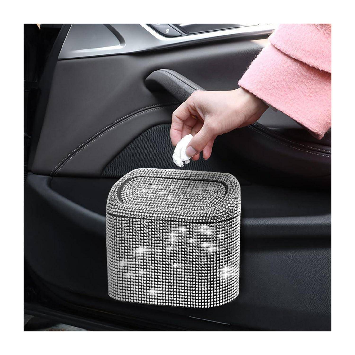 Eine Hand wischt Flecken von einem mit Kristallen bedeckten Auto-Taschentuchbox ab, die an der Innenseite einer Autotür montiert ist.