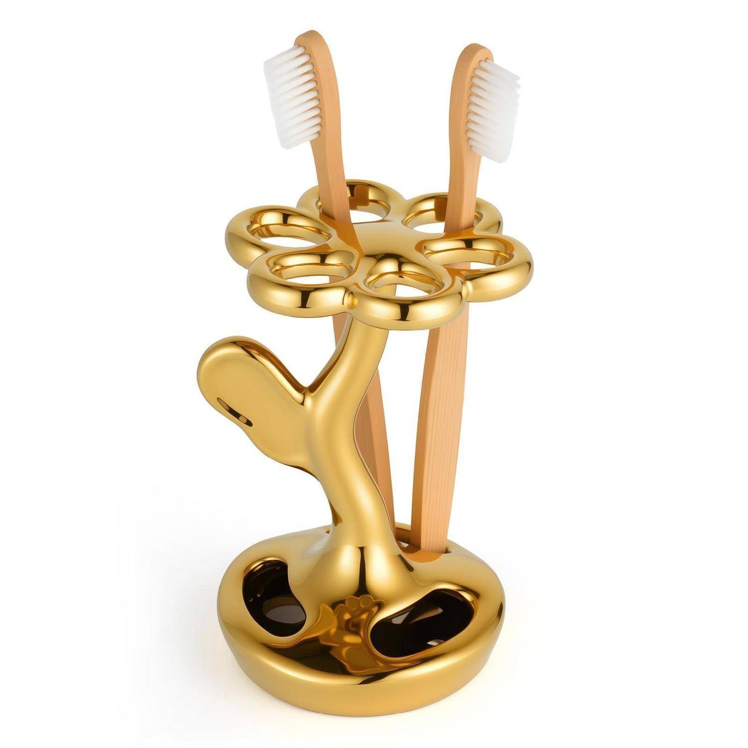 Goldener Zahnburstenbehälter in Form eines Baumes, der zwei Zahnbürsten auf weißem Hintergrund hält.