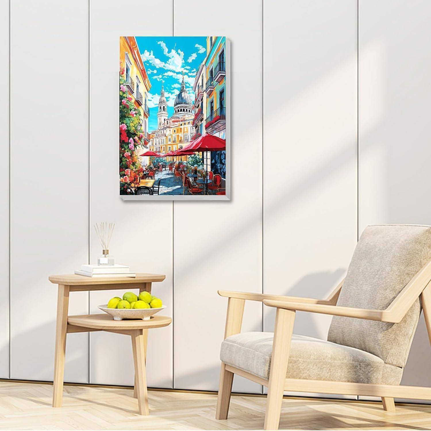 Helles Wohnzimmer mit einem beigen Sessel, einem kleinen Holzbeistelltisch und einem farbenfrohen gerahmten Gemälde einer Stadtstraße an der Wand.
