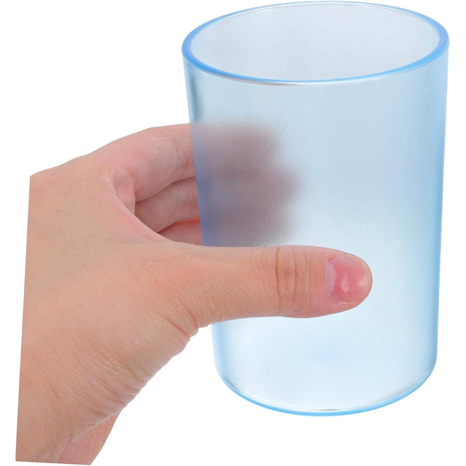 Eine Hand hält einen durchsichtigen blauen Plastikbecher auf weißem Hintergrund.