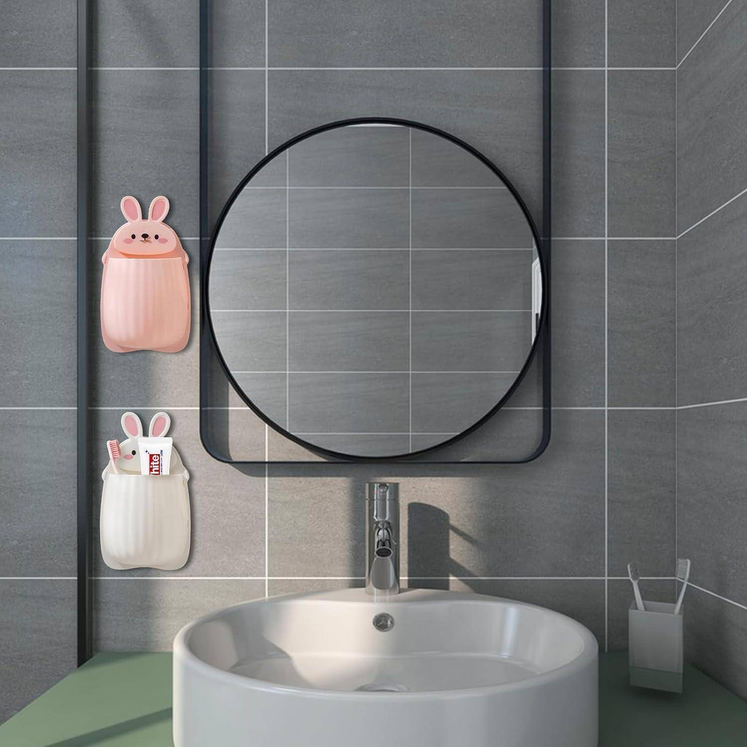 Modernes Badezimmerbecken mit rundem Spiegel, wandmontiertem Wasserhahn und zwei hasenförmigen Aufbewahrungstaschen, die Toilettenartikel enthalten.