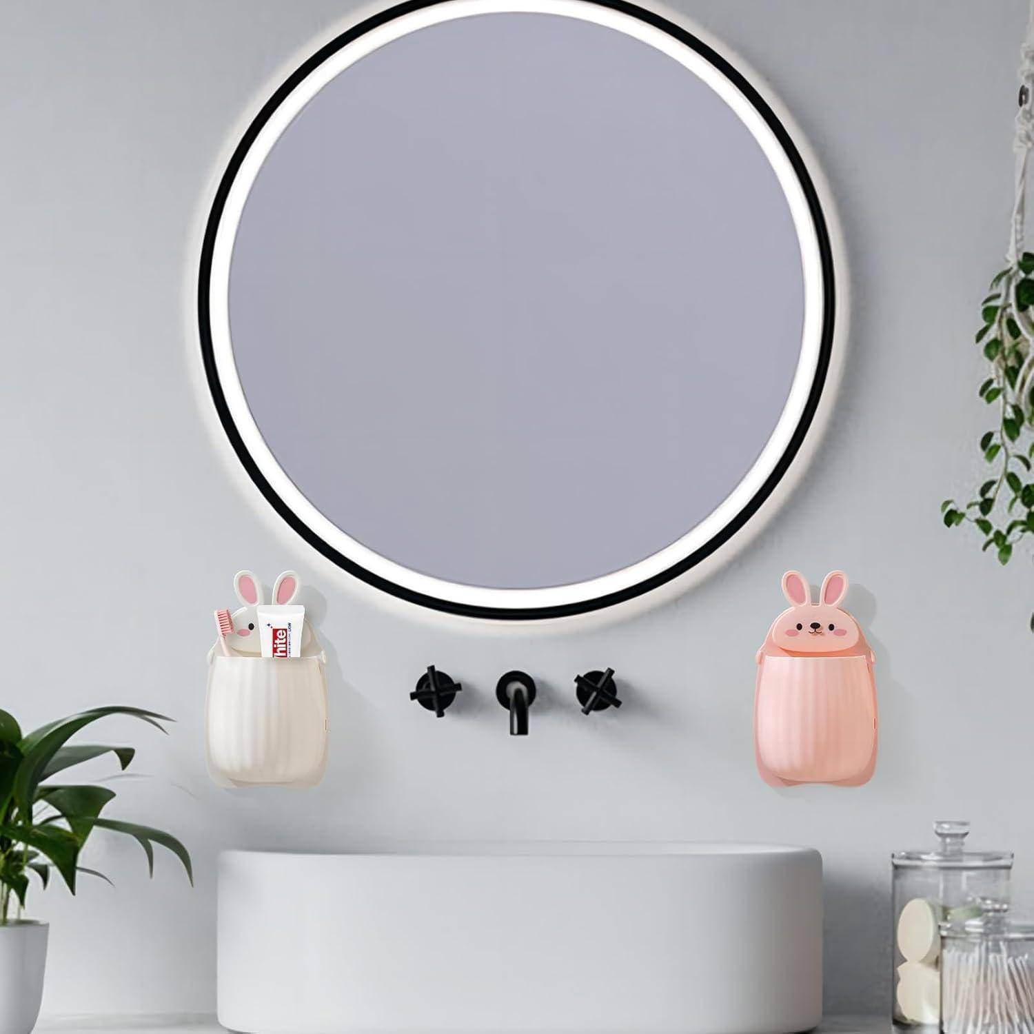 Modernes Badezimmer-Waschtisch mit rundem hinterleuchtetem Spiegel über einem weißen Waschbecken, flankiert von hasenmotiv-Wandorganizern und einer kleinen Pflanze.