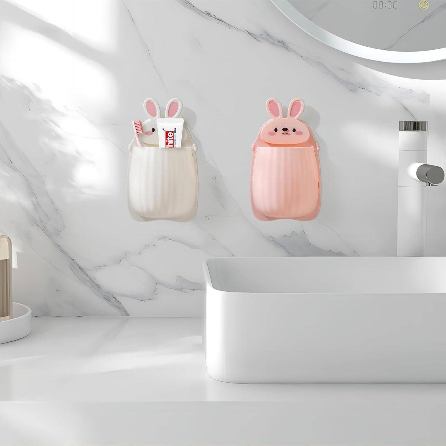 Zwei an der Wand montierte Aufbewahrungstaschen in Kaninchenform, eine weiße und eine rosa, halten kleine Toilettenartikel über einem Badezimmerspiegel.