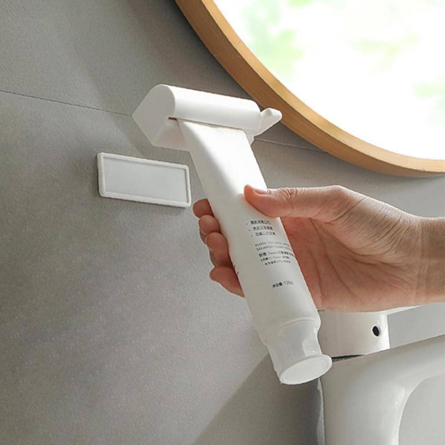 Eine Hand hält eine weiße röhrenförmige Reinigungsdüse oder ein Aufsatz in der Nähe eines wandmontierten Halters in einem Badezimmer oder einem ähnlichen Raum.